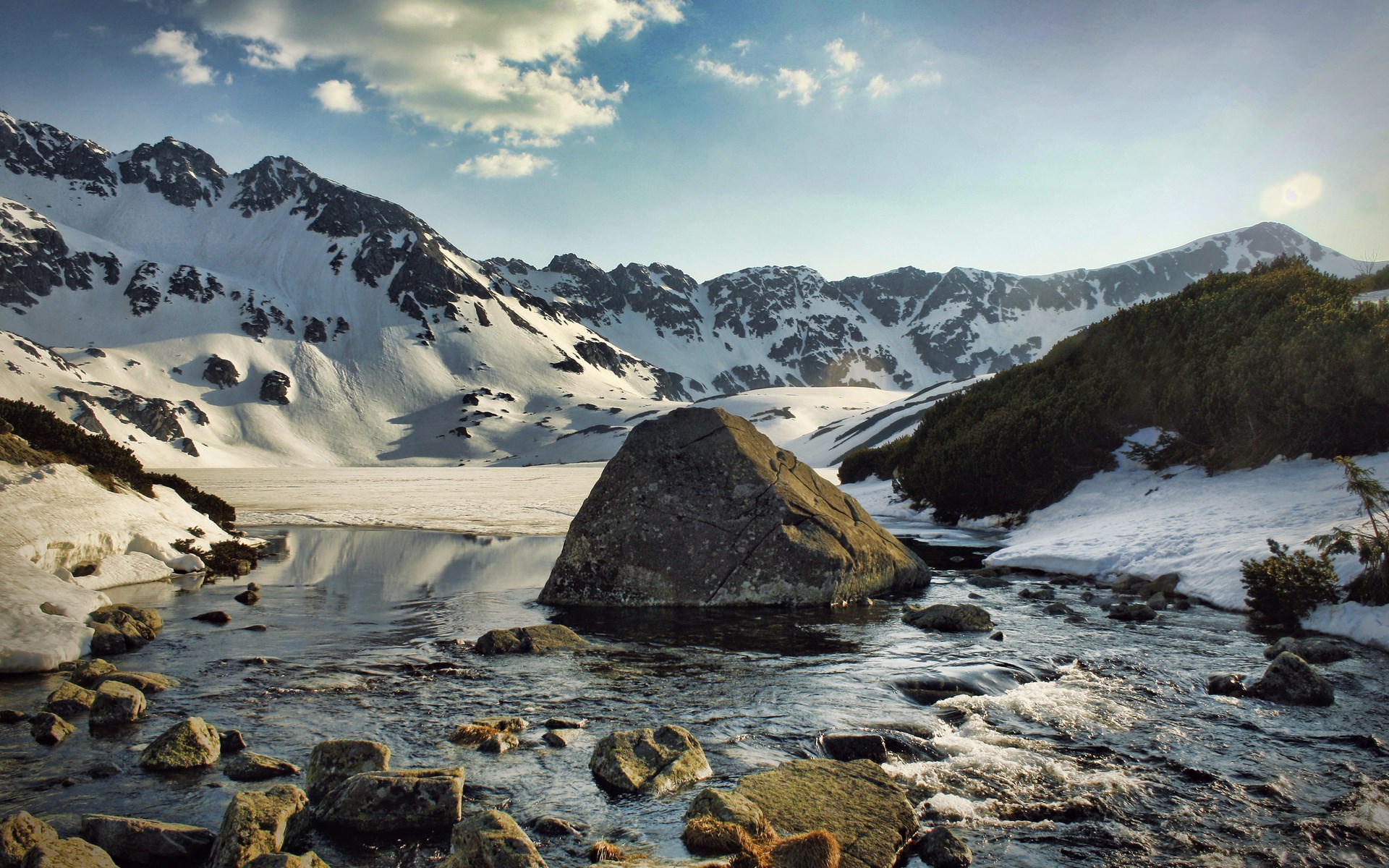Snowy mountains and a rocky stream HD Wallpaper
