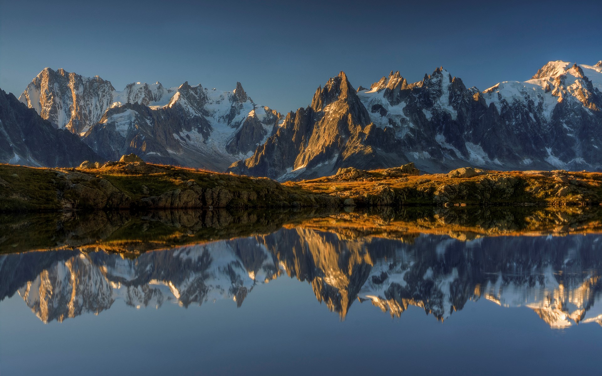 Snow-capped mountains reflected in a calm lake HD Wallpaper