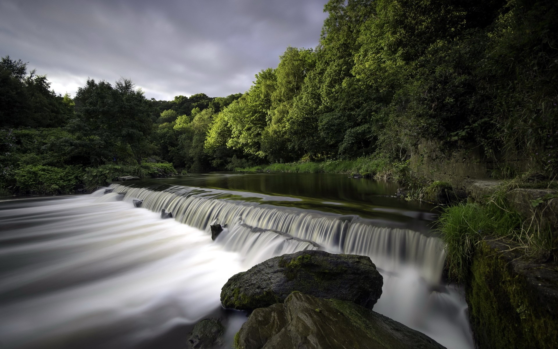 Waterfall flowing over rocks with trees in the background HD Wallpaper