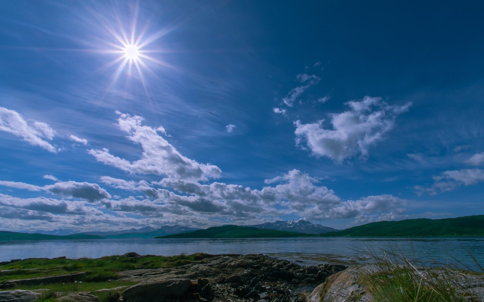 Sun over a calm bay with mountains in the distance HD Wallpaper