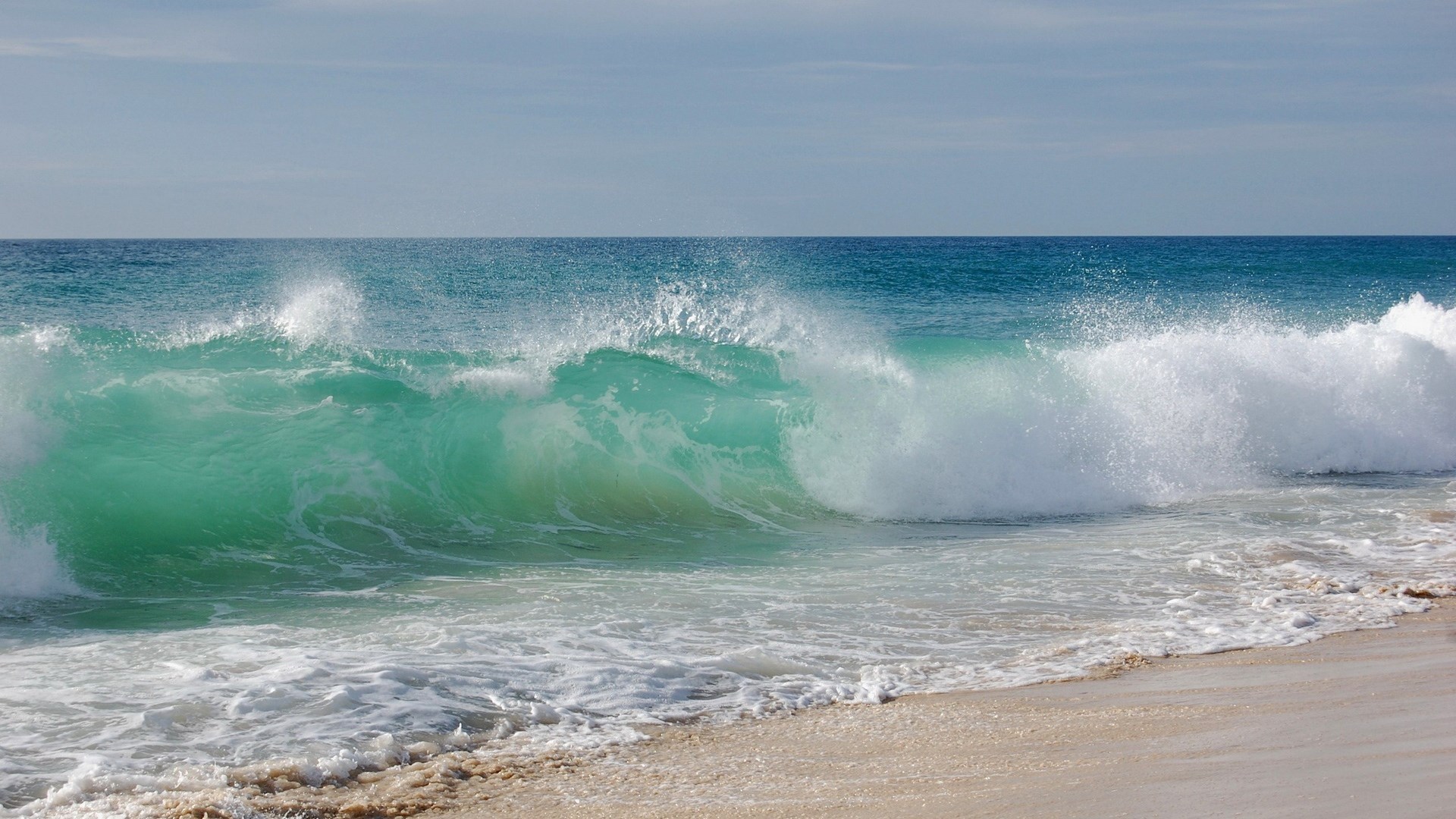 Ocean wave crashing on a sandy beach HD Wallpaper