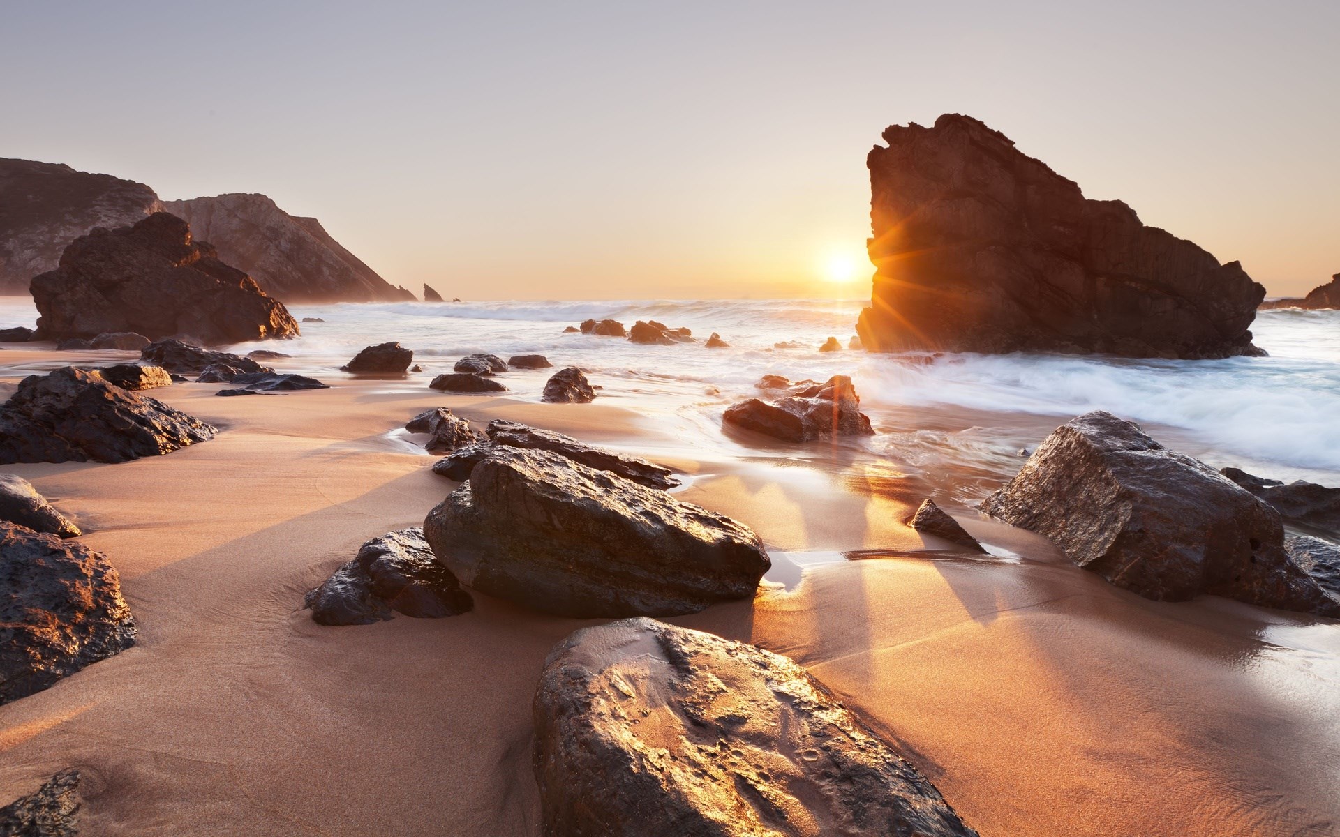 Sunset over a rocky beach with waves HD Wallpaper