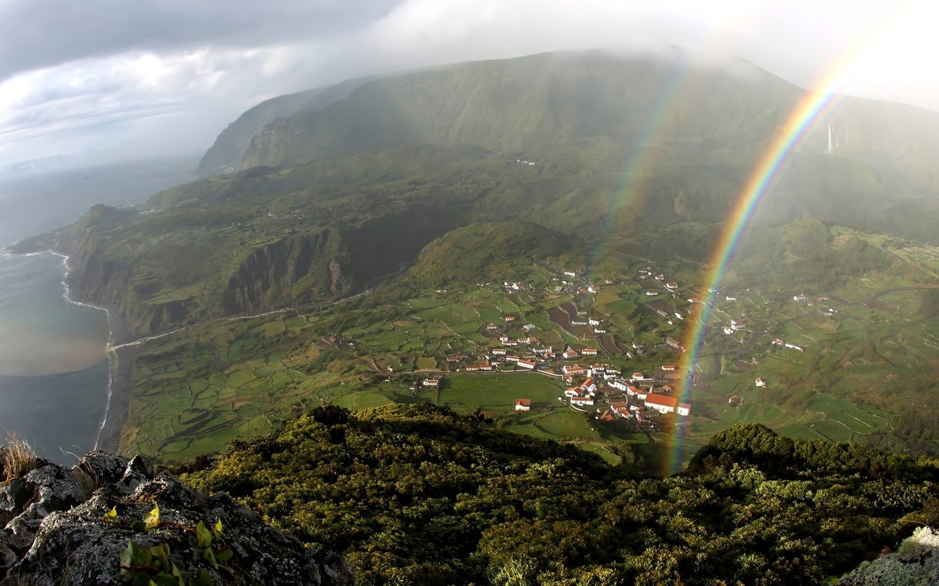 Rainbow over a coastal village on a green island HD Wallpaper
