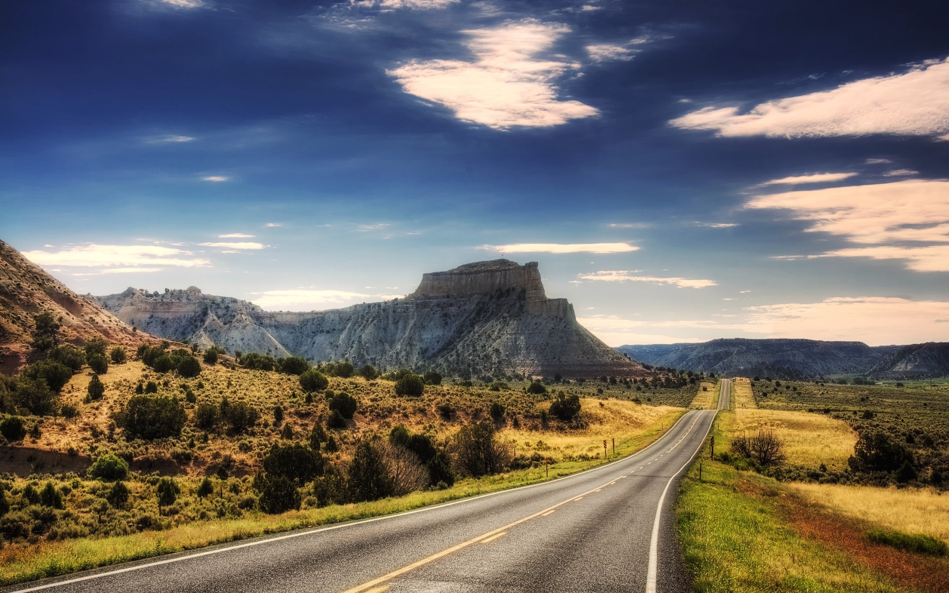 Scenic highway through a desert landscape with mesas HD Wallpaper