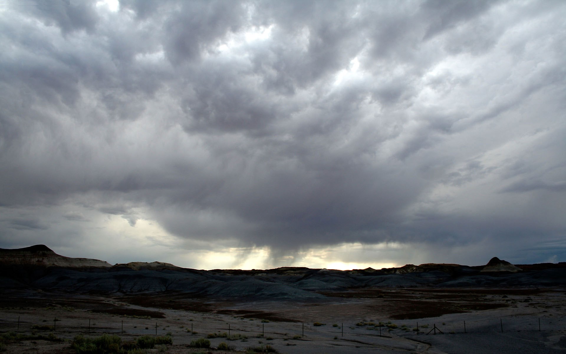 Storm clouds over a barren landscape HD Wallpaper