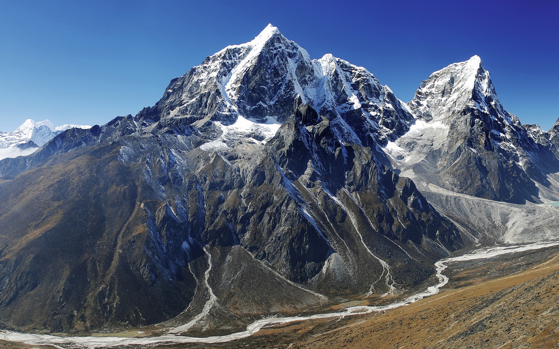 Snow-capped mountains and a riverbed under a clear blue sky HD Wallpaper