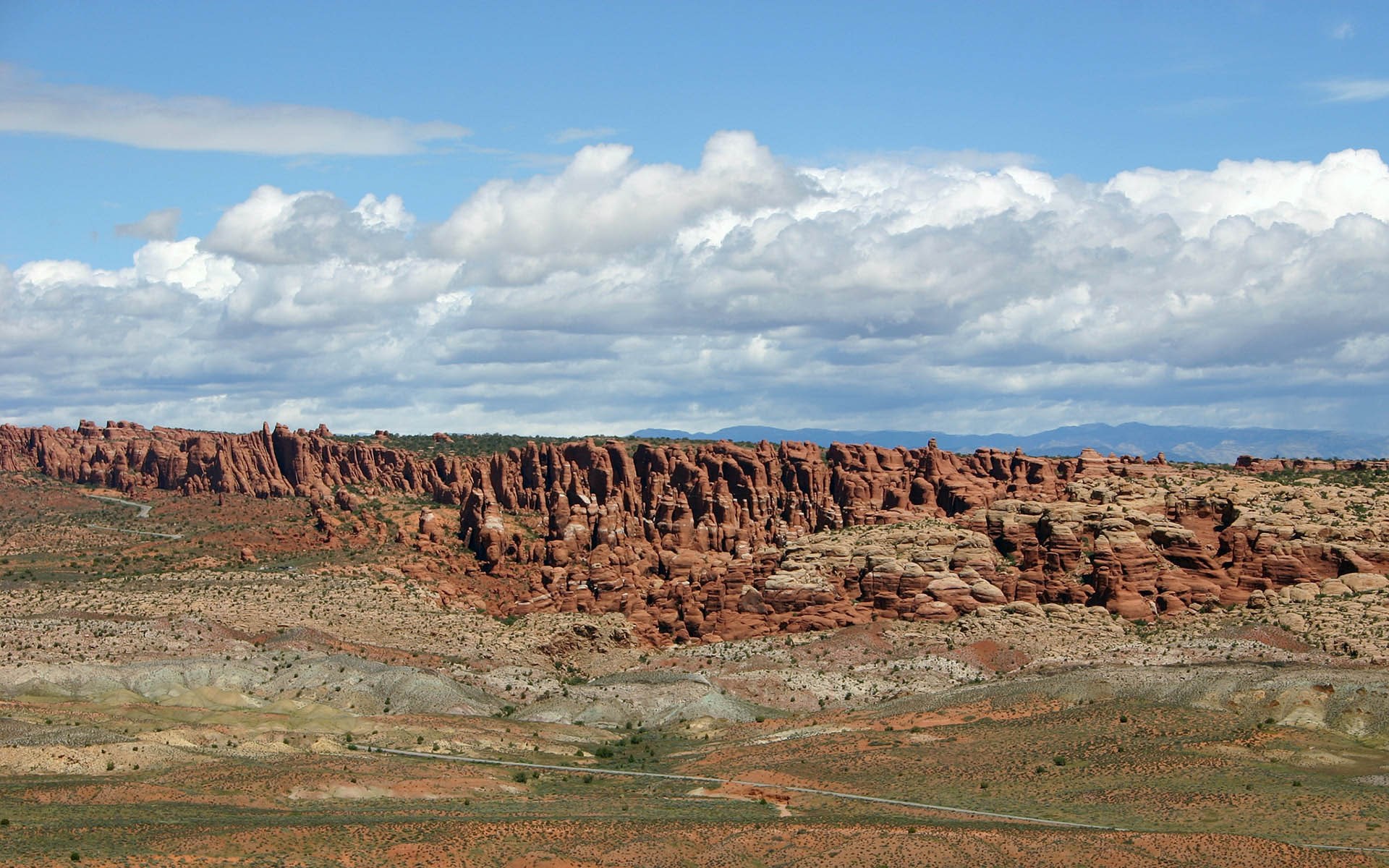 Desert landscape with red rock formations and clouds HD Wallpaper