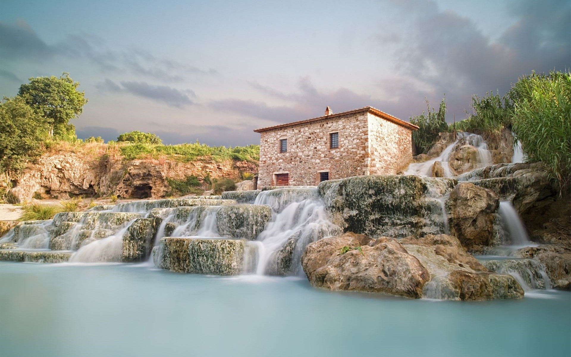 Stone building by cascading waterfalls HD Wallpaper