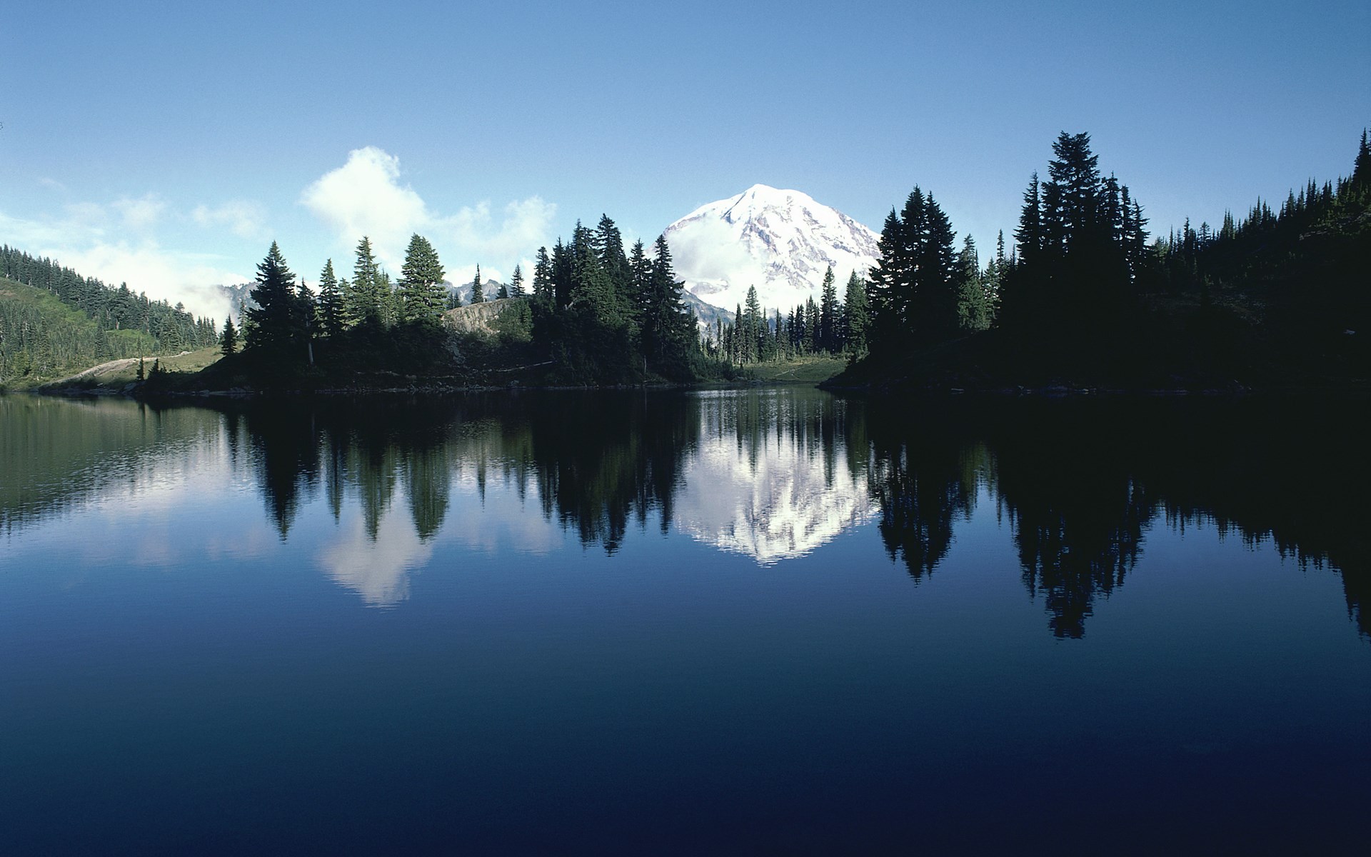 Snow-capped mountain reflected in a calm lake with pine trees HD Wallpaper