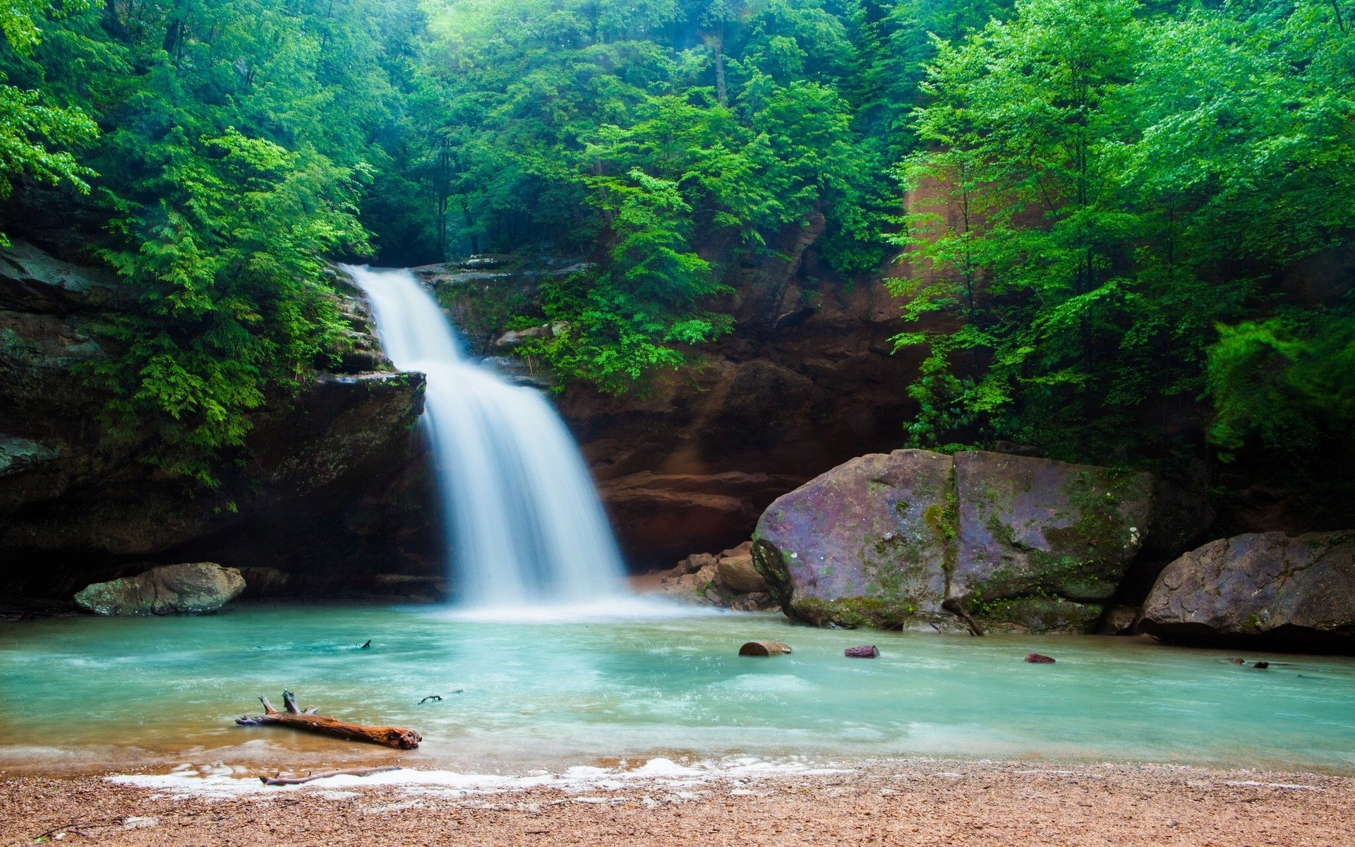 Waterfall cascading into a turquoise pool in a lush forest HD Wallpaper