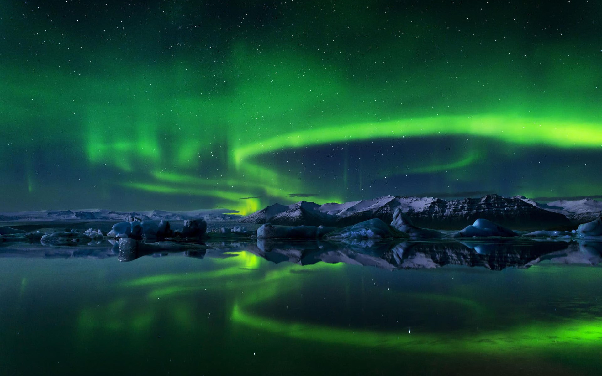 Aurora Borealis over icy lake and mountains HD Wallpaper