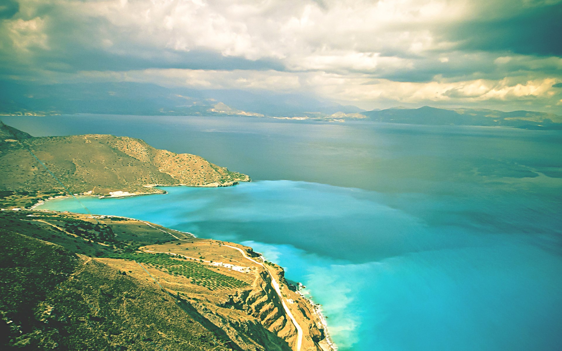 Aerial view of a turquoise bay and rugged coastline HD Wallpaper
