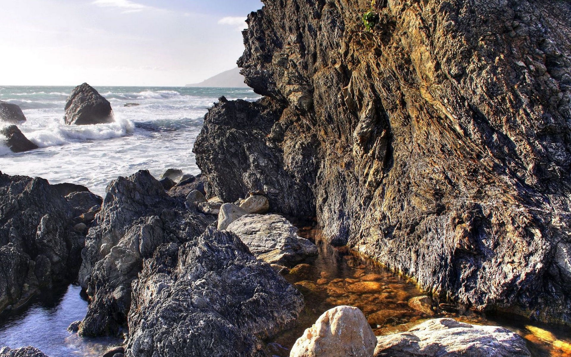 Rocky coastline with waves crashing against rocks HD Wallpaper