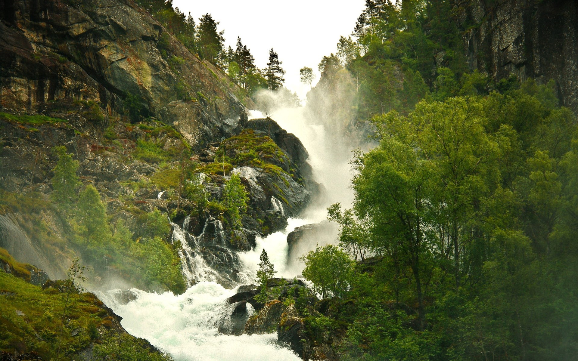 Waterfall cascading down a rocky mountain with trees HD Wallpaper