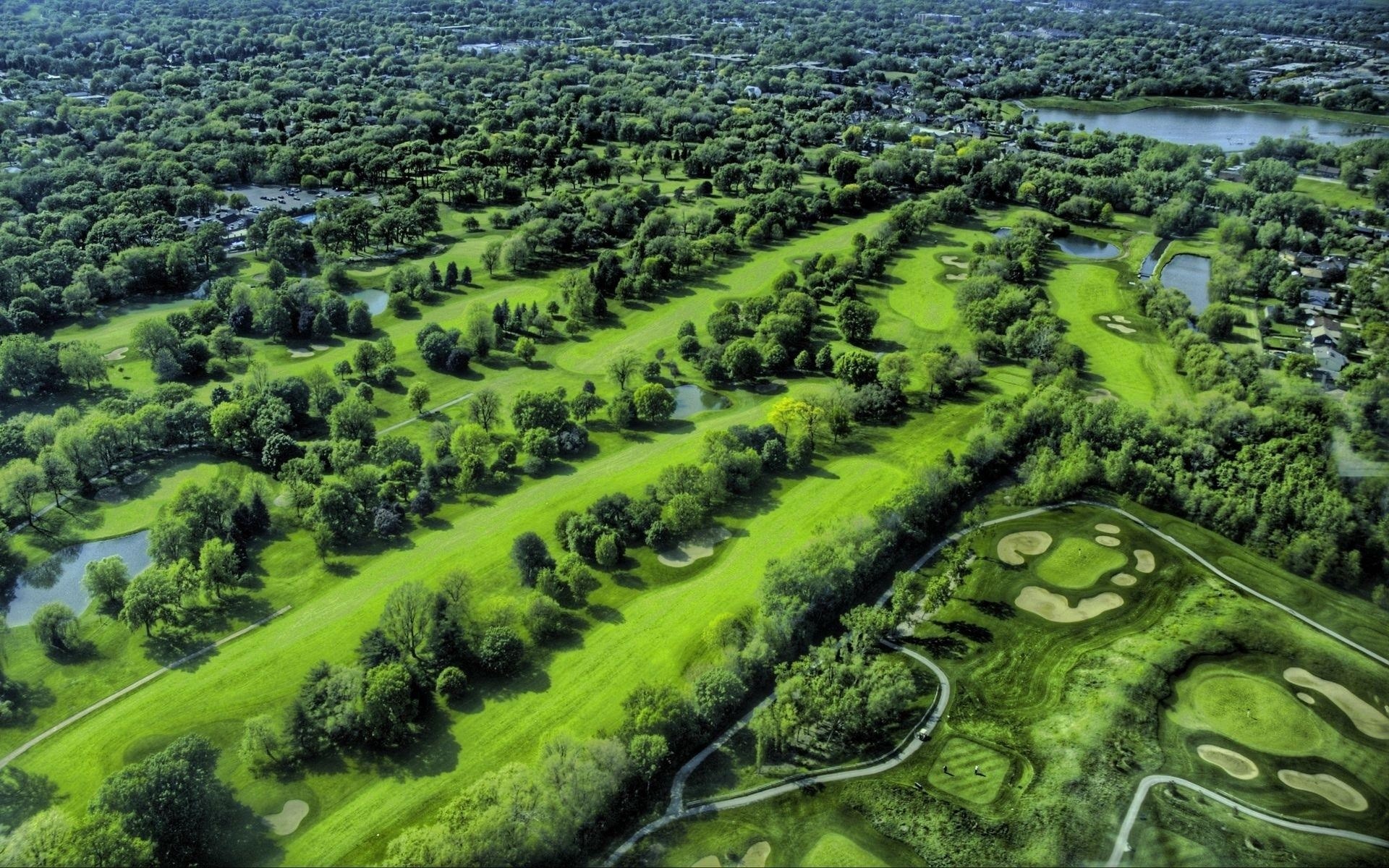 Aerial view of a golf course with trees and water HD Wallpaper