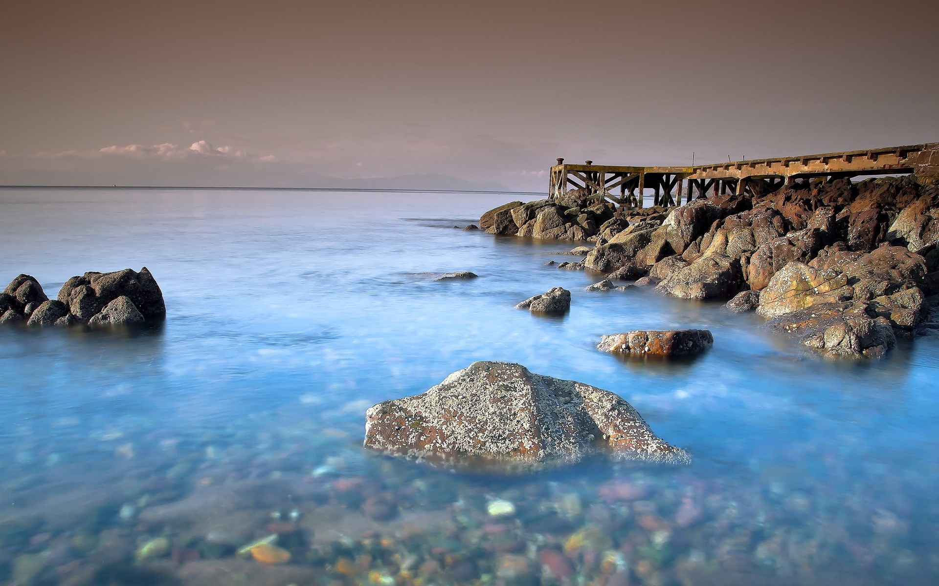 Wooden pier and rocks by the sea HD Wallpaper