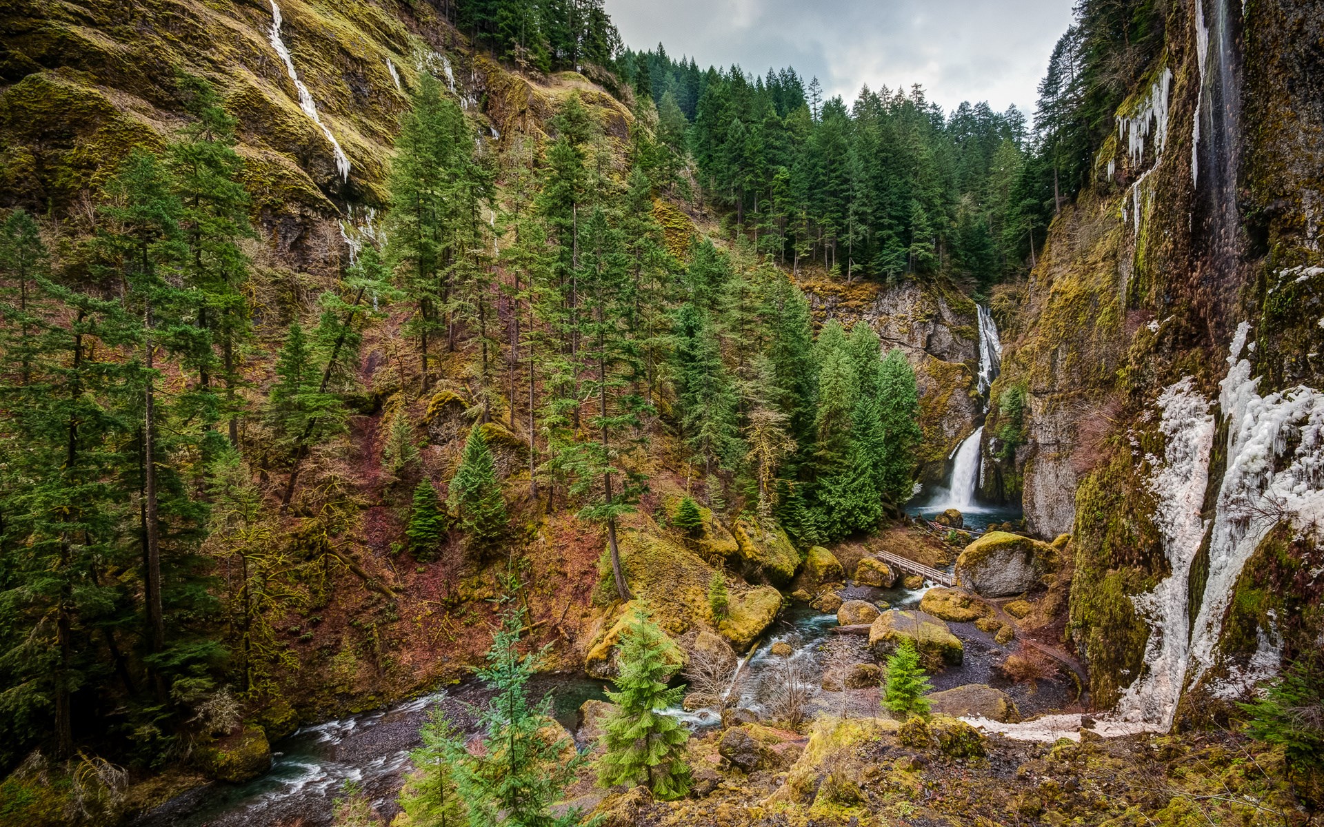 Waterfall cascading down a mossy cliff face HD Wallpaper