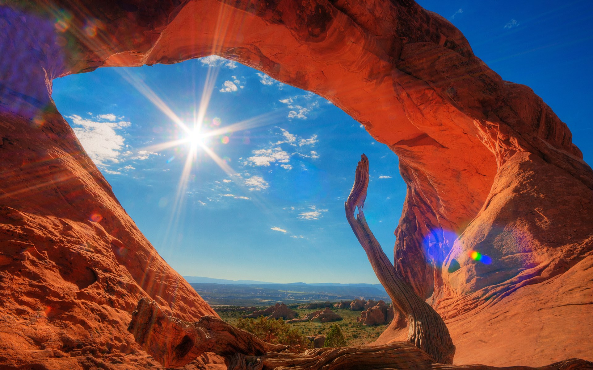Natural arch framing a sunlit desert landscape HD Wallpaper