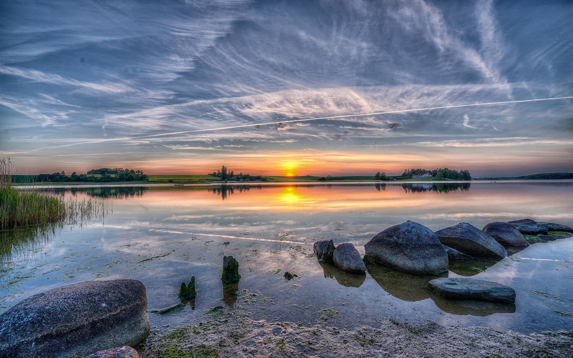 Sunset over a calm lake with rocks in the foreground HD Wallpaper