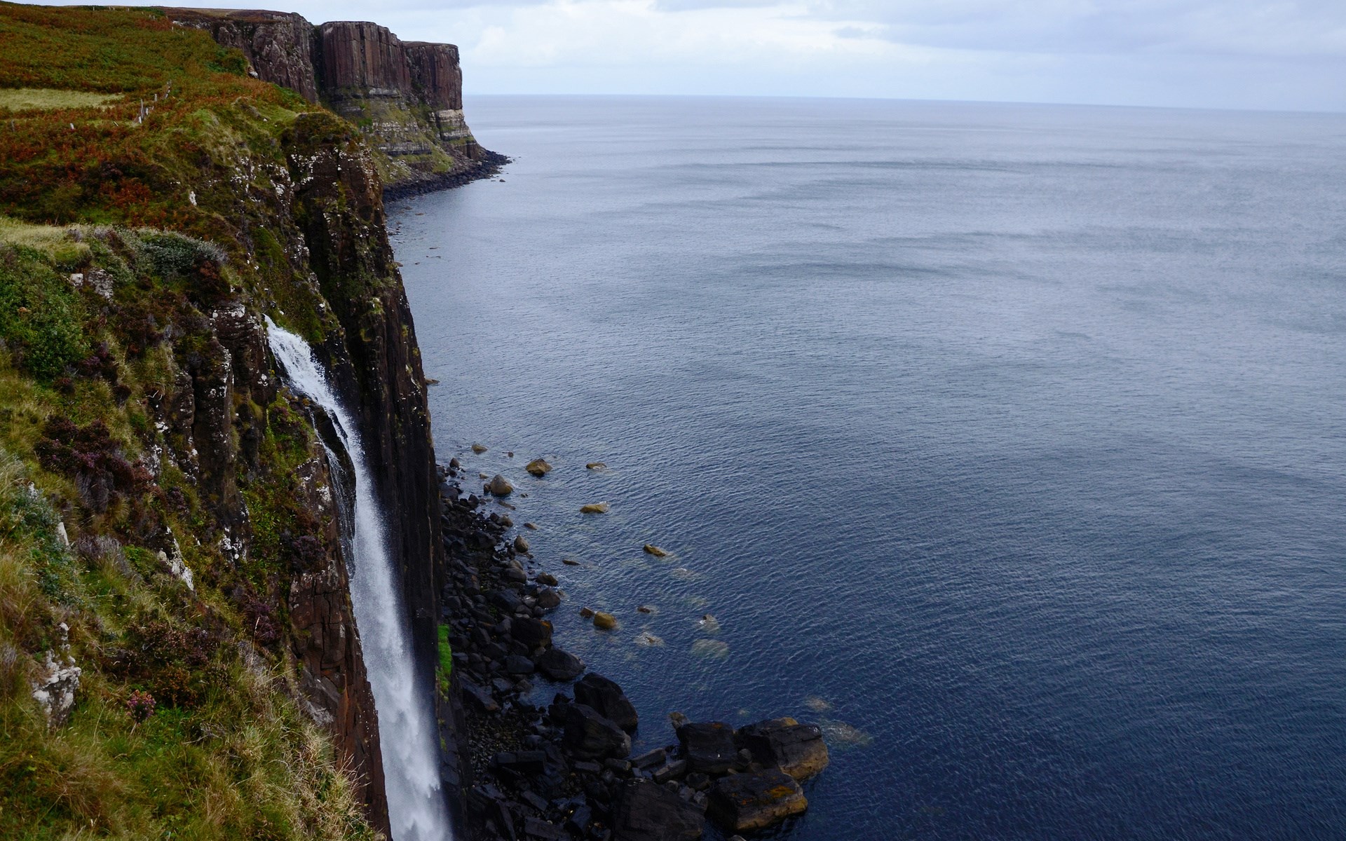Waterfall cascading down a cliff into the sea HD Wallpaper