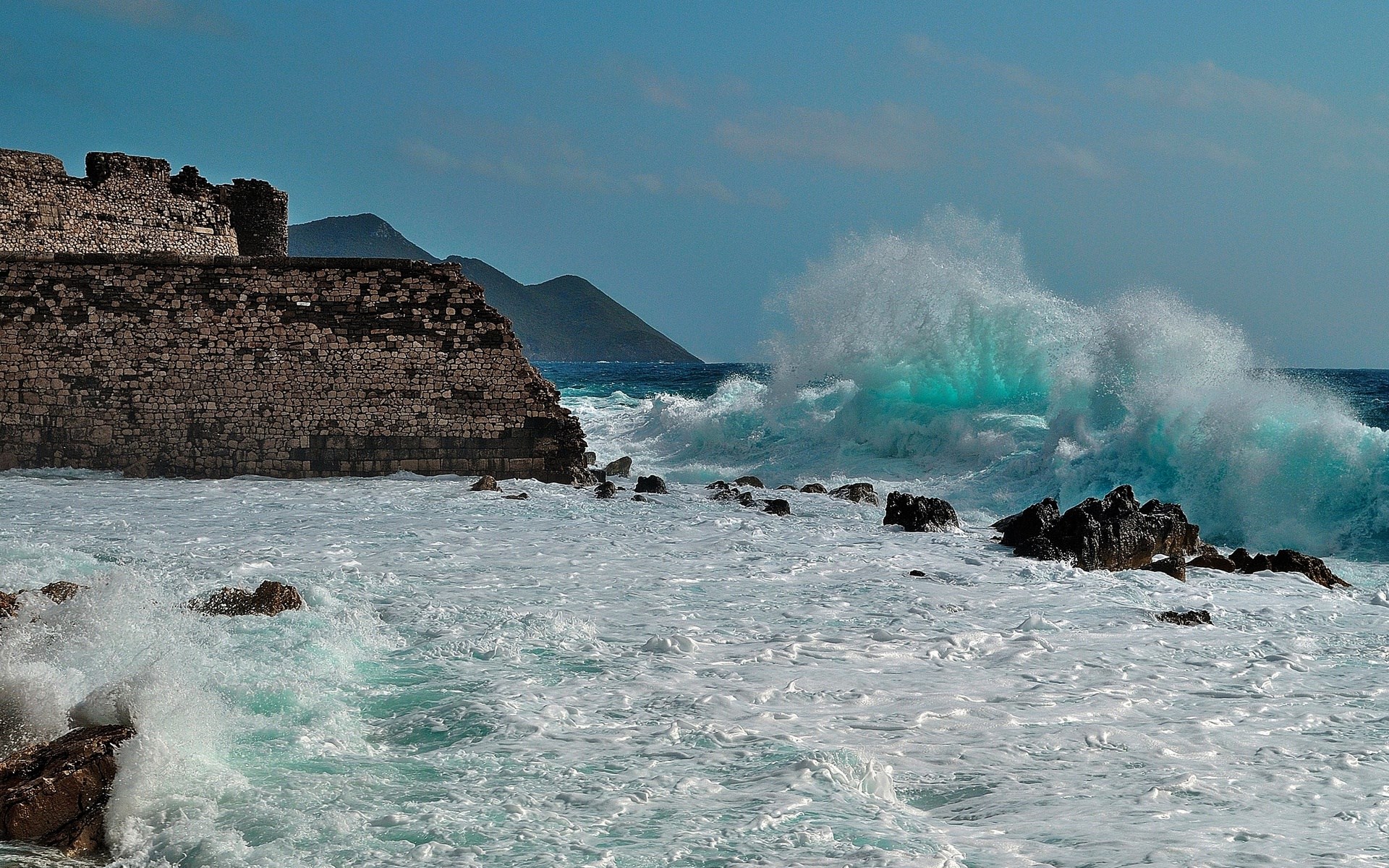 Waves crashing against ancient stone ruins by the sea HD Wallpaper