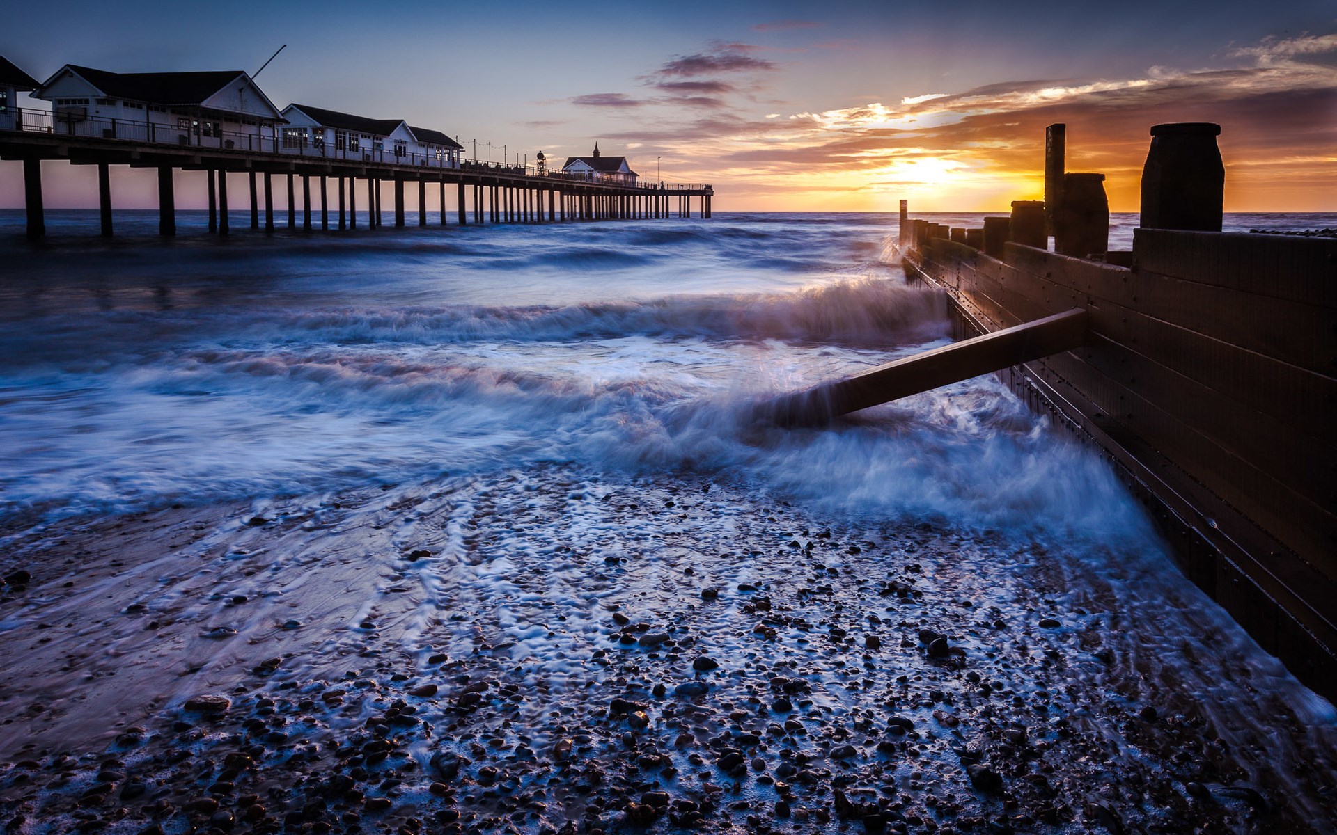 Pier over the sea at sunset with waves HD Wallpaper