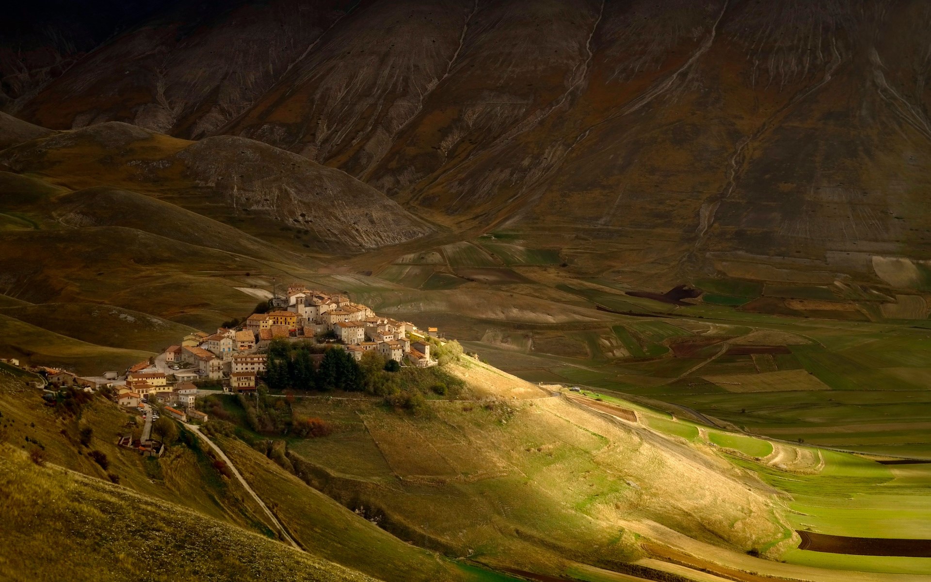 Hilltop village in a valley with mountains HD Wallpaper