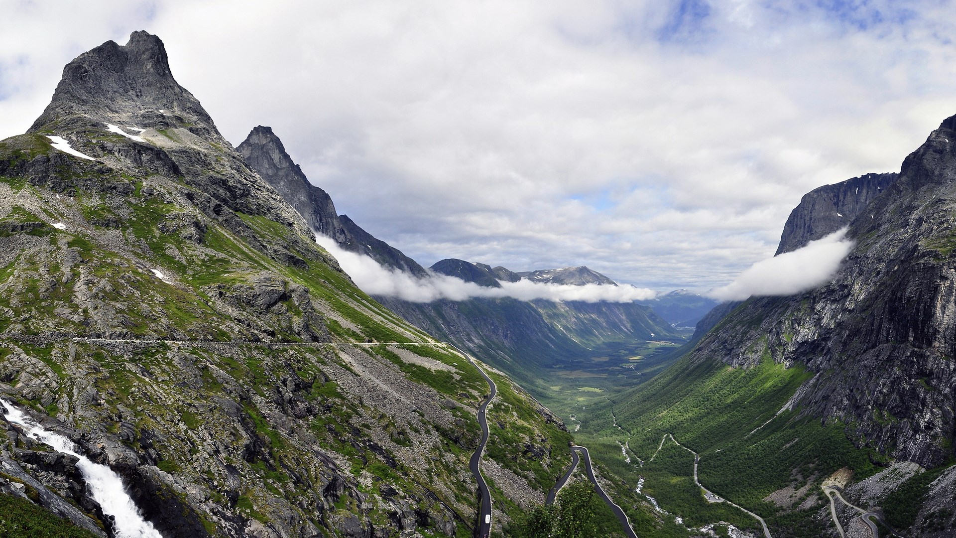 Winding road through a mountain valley with clouds HD Wallpaper