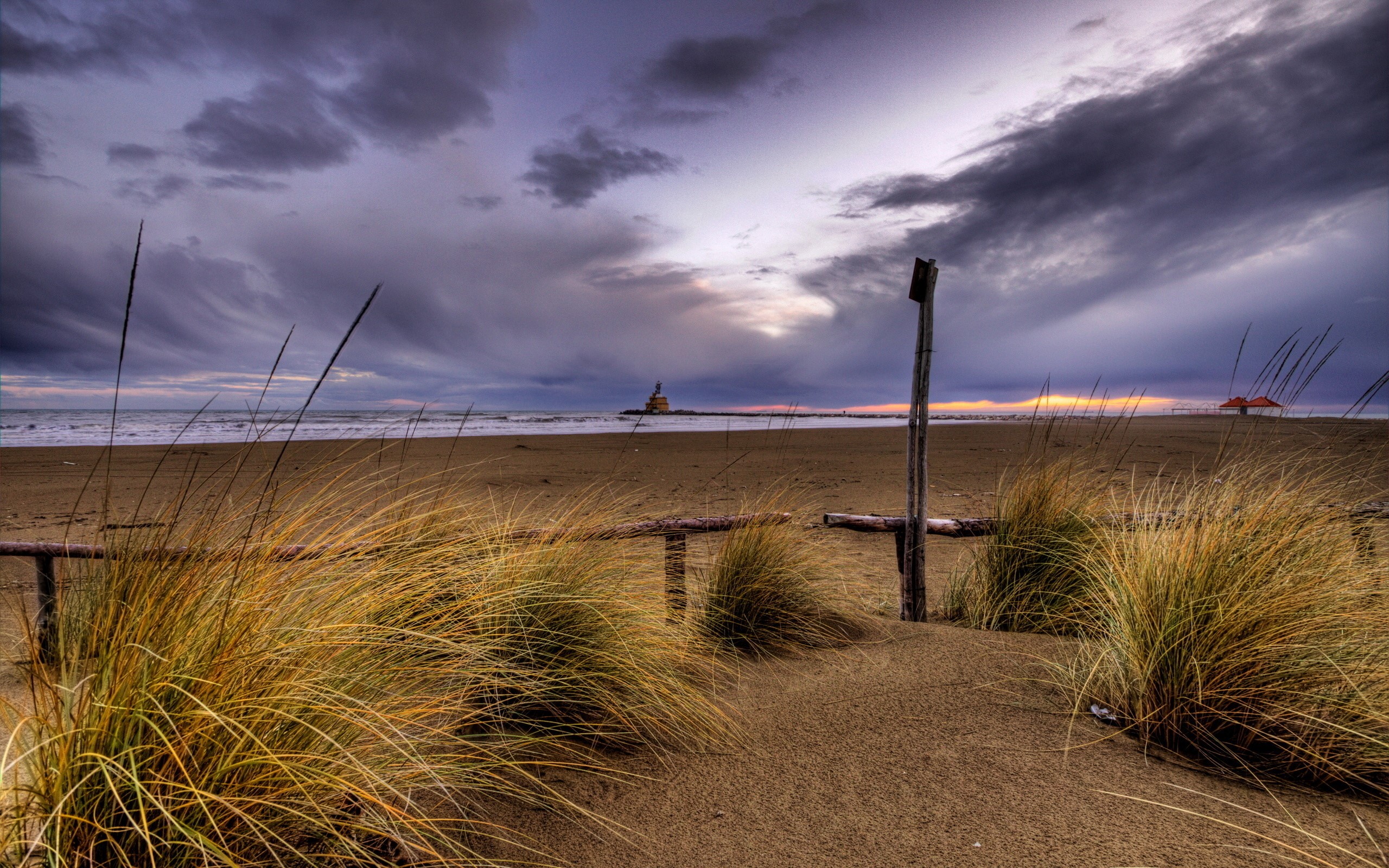 Beach with lighthouse and stormy sky HD Wallpaper