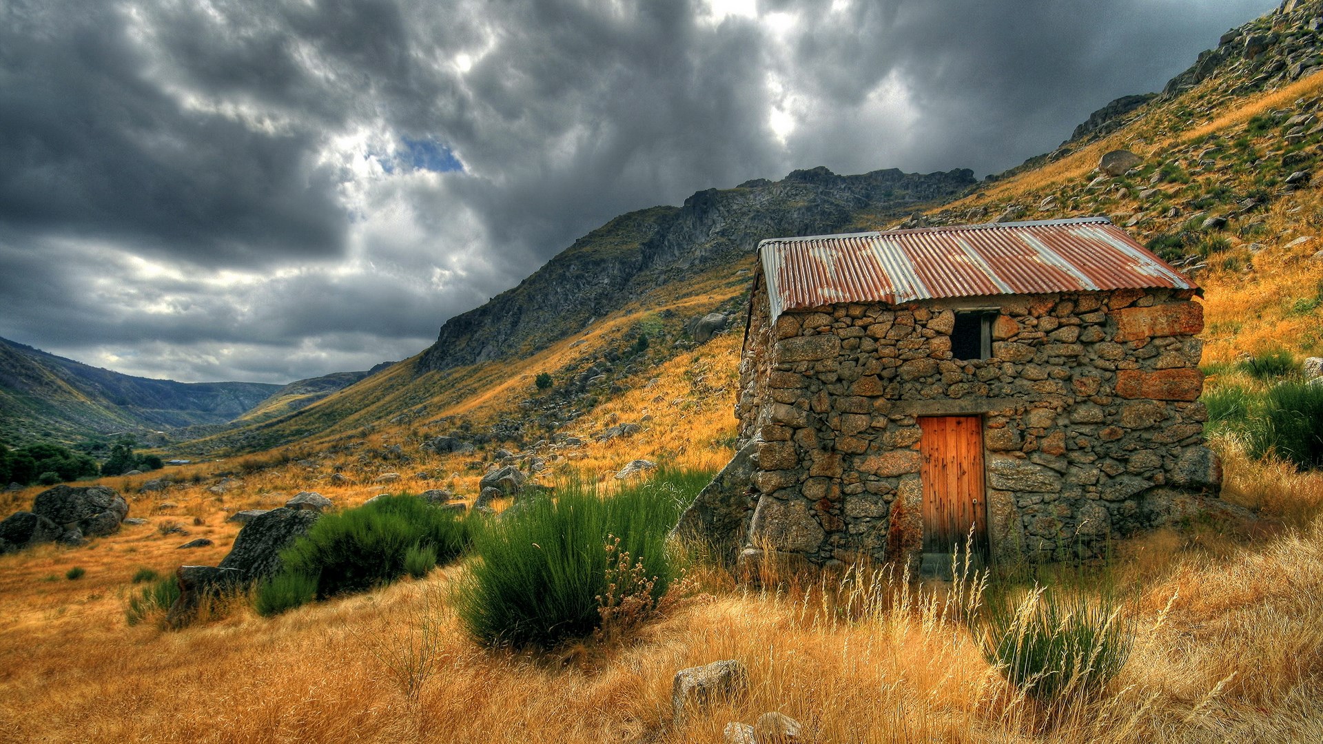 Stone cabin in a mountain valley under a cloudy sky HD Wallpaper