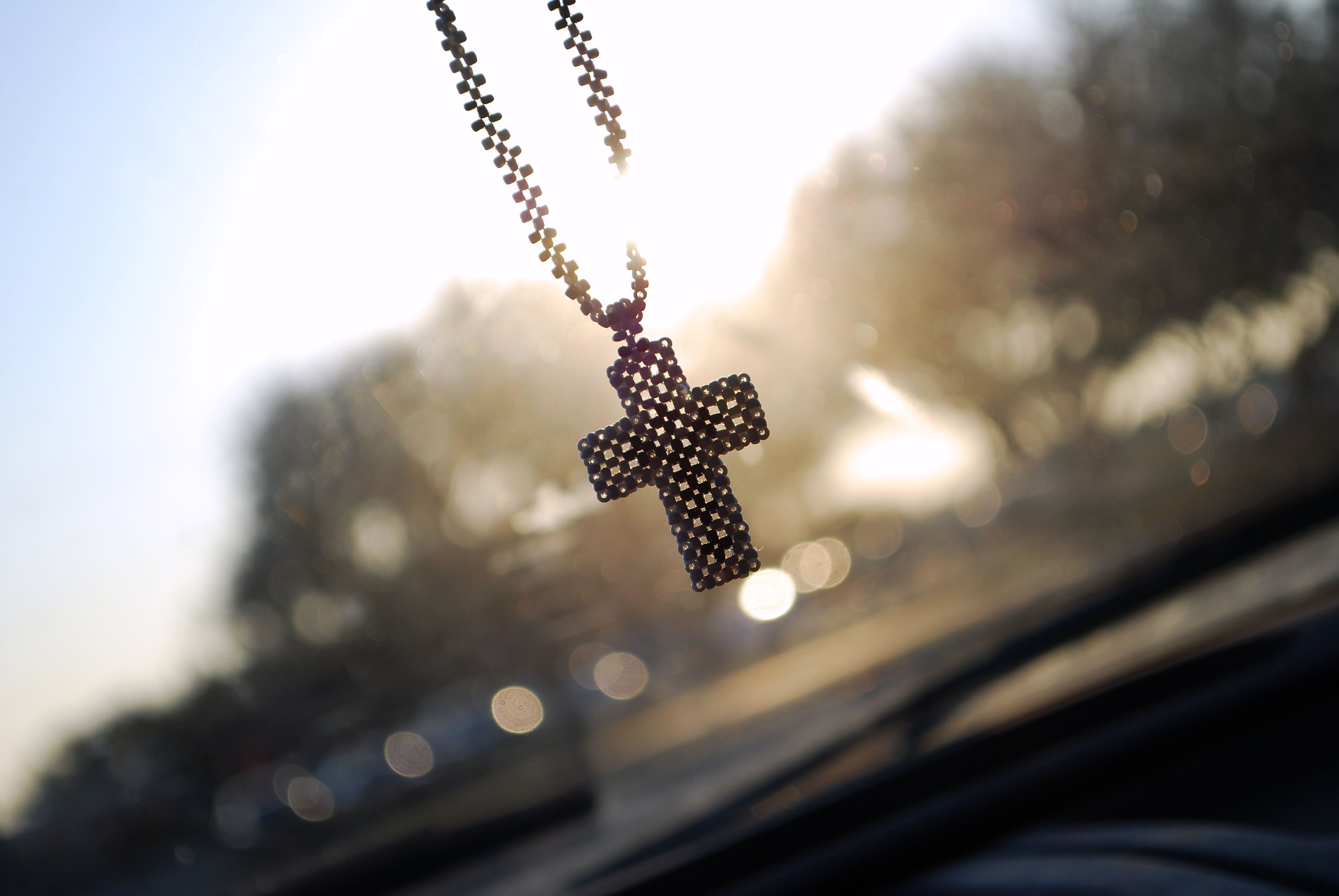 Cross necklace hanging in sunlight HD Wallpaper