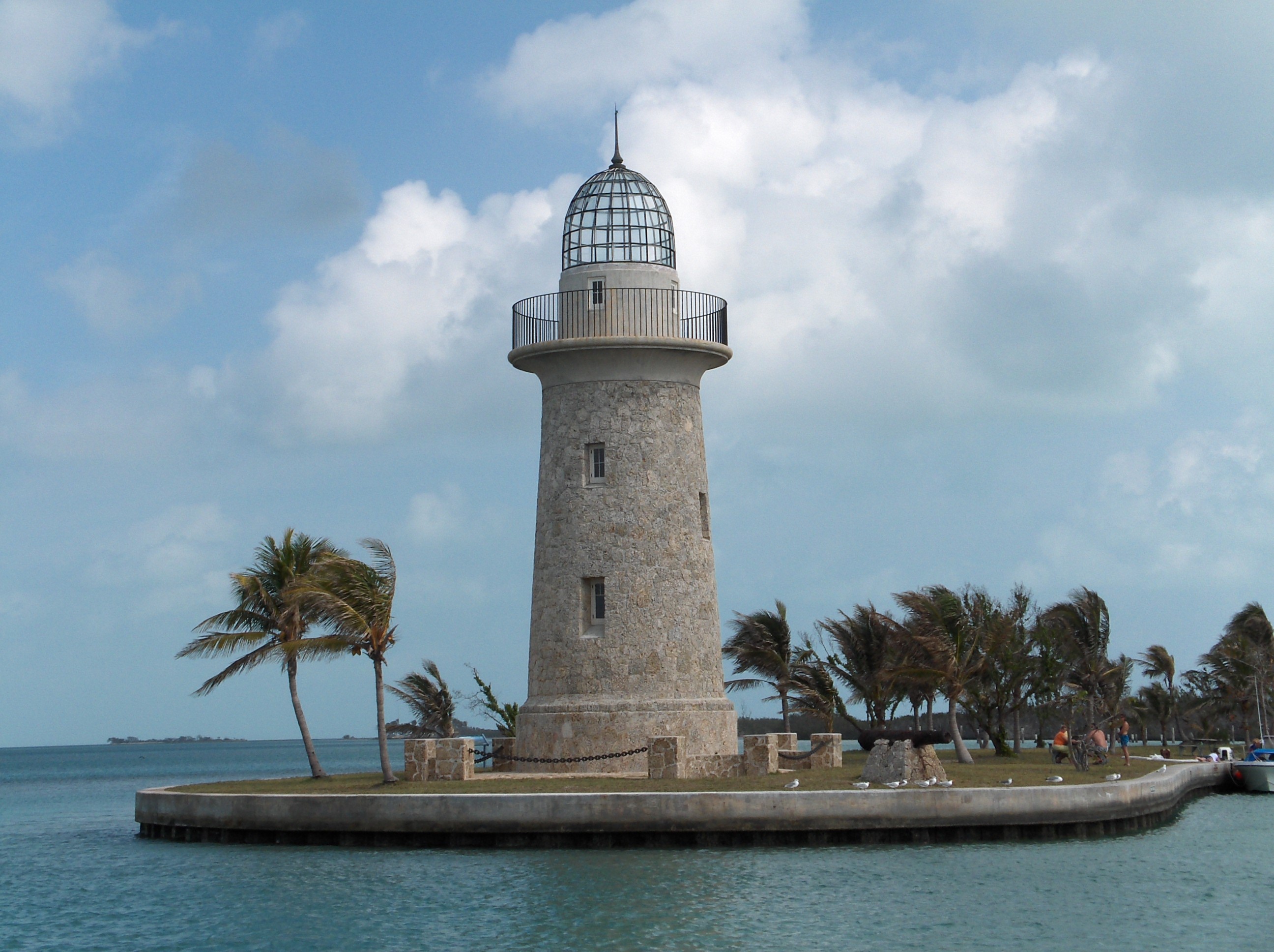 Stone lighthouse on a small island with palm trees HD Wallpaper
