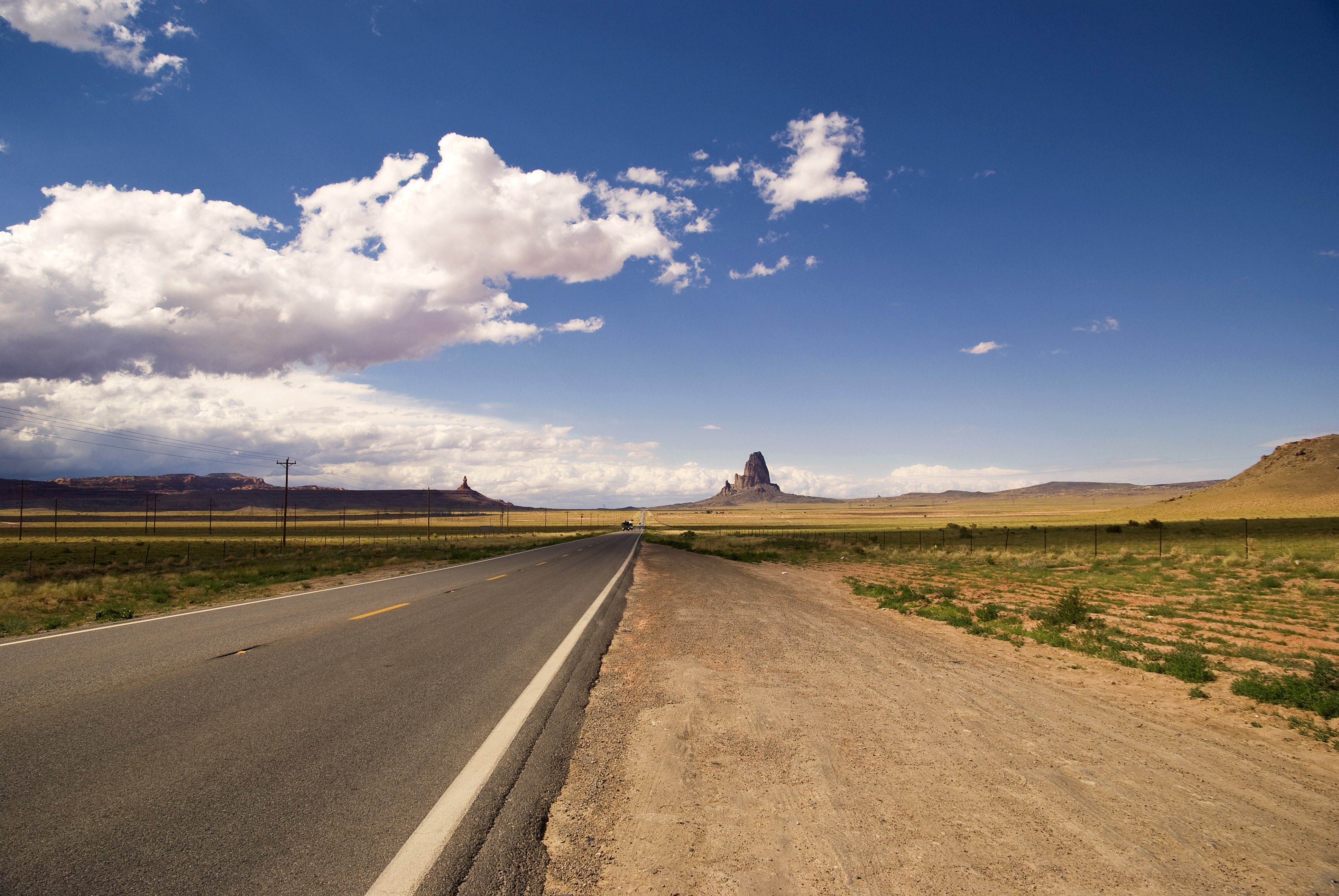 Road through Monument Valley under a cloudy sky HD Wallpaper