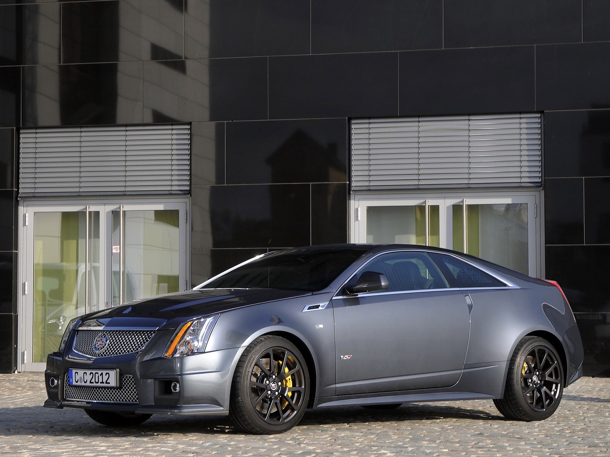 Cadillac CTS-V Coupe in front of a modern building HD Wallpaper