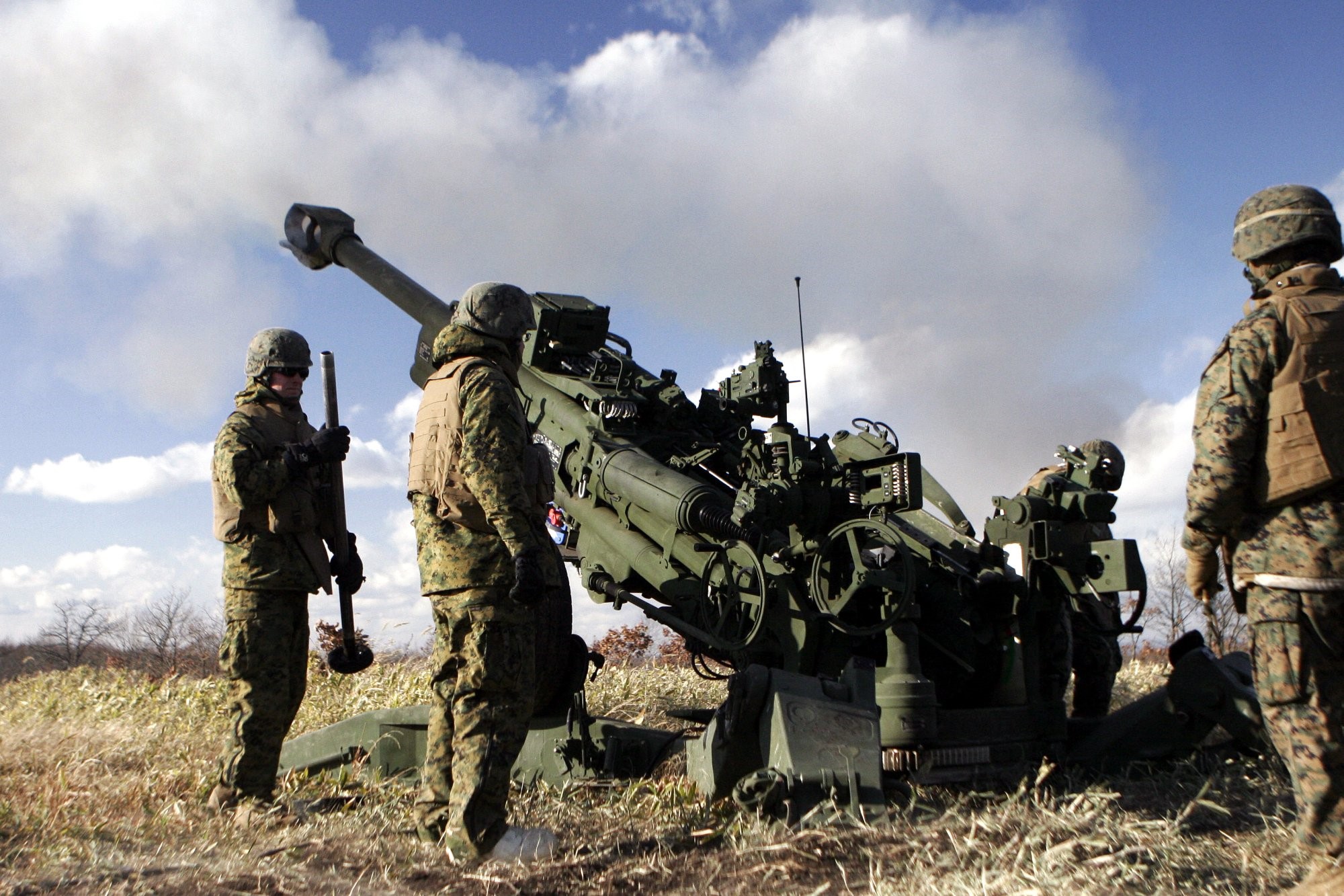 Marines operate a large artillery cannon in a field HD Wallpaper