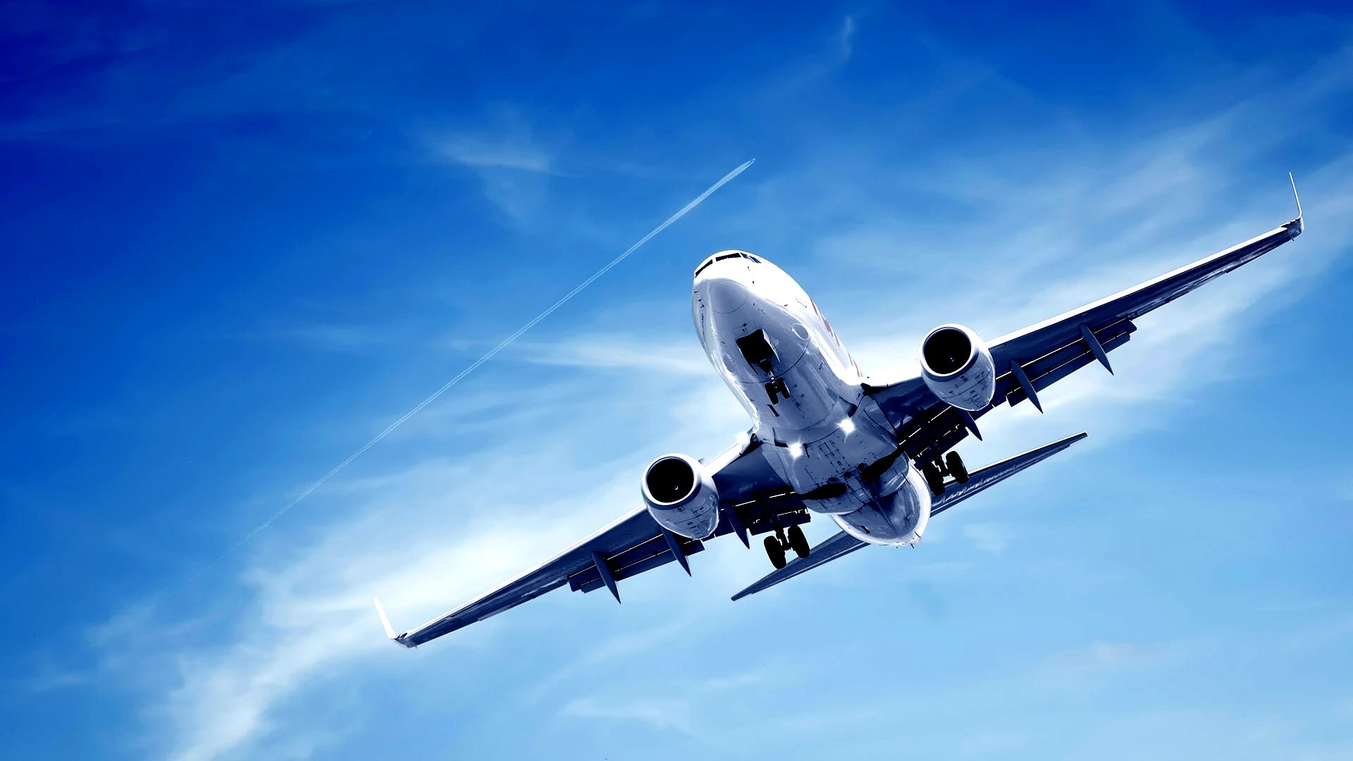 Airplane flying in a bright blue sky with contrails HD Wallpaper