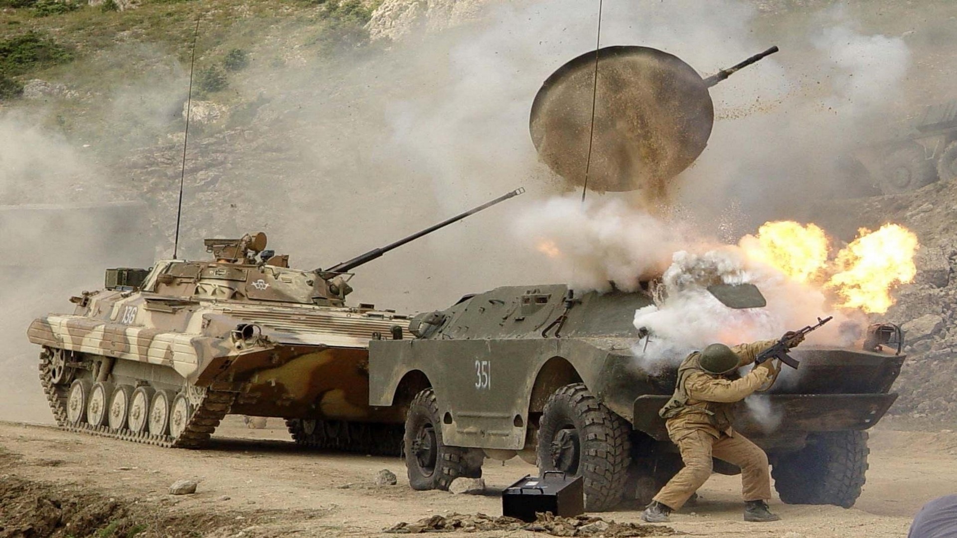 Military vehicles in combat with explosions and smoke HD Wallpaper