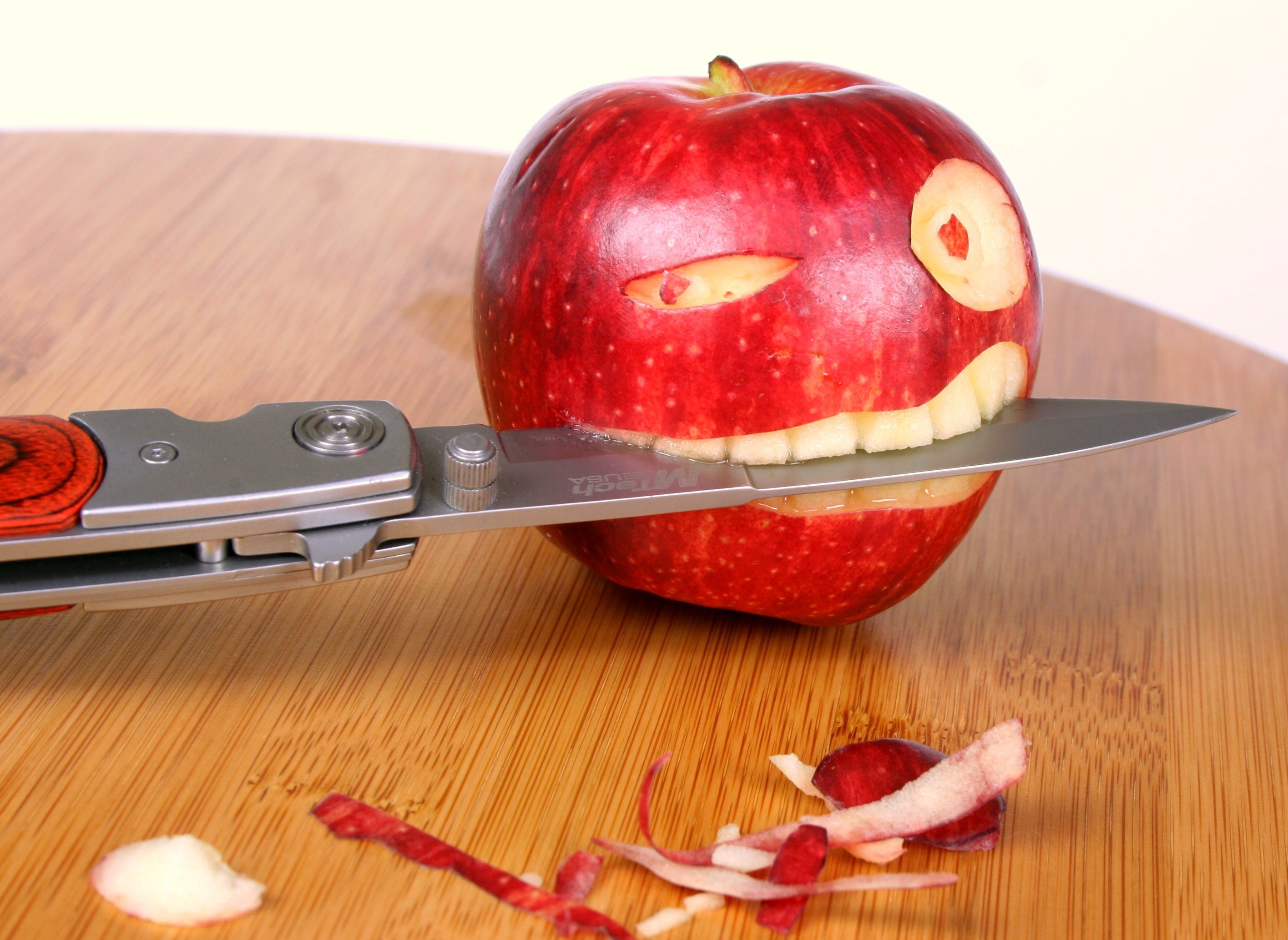Apple carved into a face with a knife HD Wallpaper
