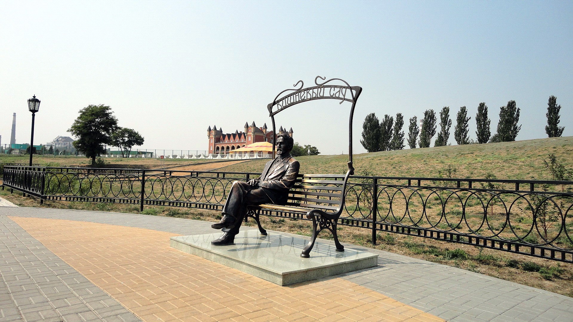 Statue of a man sitting on a bench in a park HD Wallpaper
