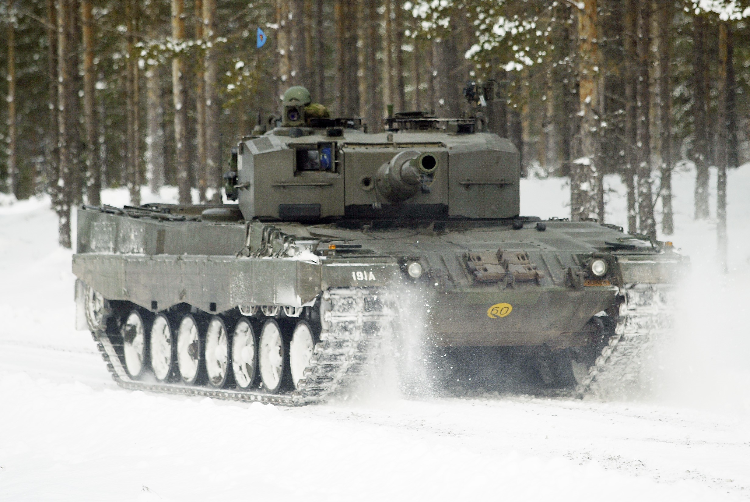 A tank drives through a snowy forest HD Wallpaper