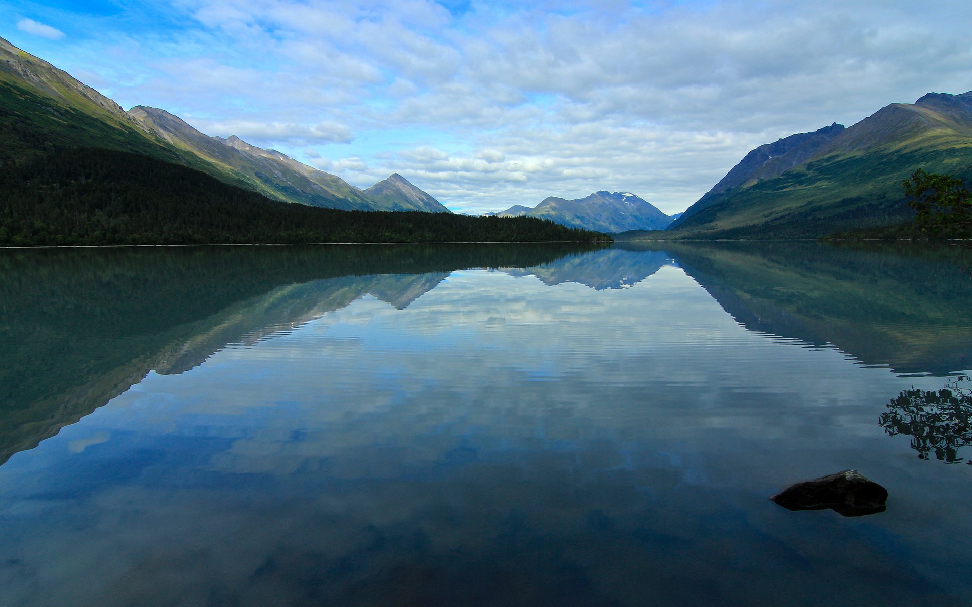 Mountains reflected in a calm lake under a cloudy sky HD Wallpaper
