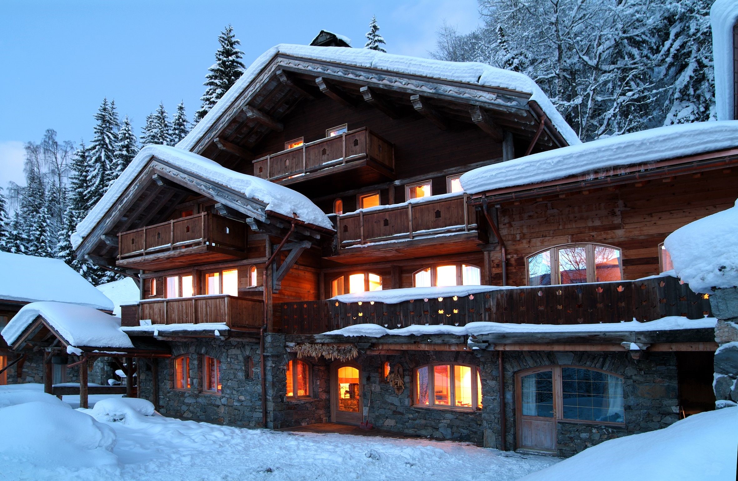 Wooden chalet with stone base in snowy mountains HD Wallpaper