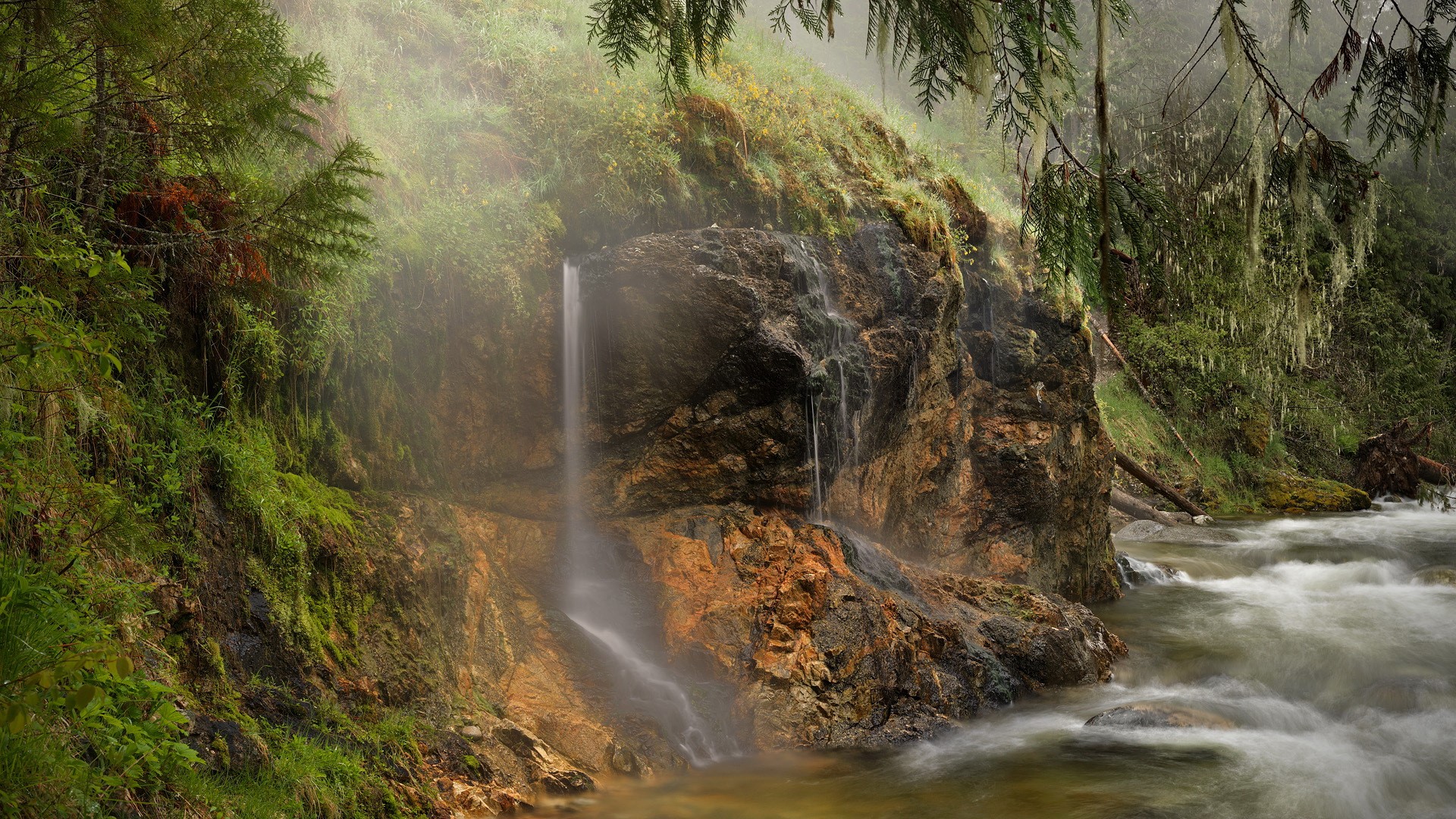 Waterfall cascading over rocks in a misty forest HD Wallpaper