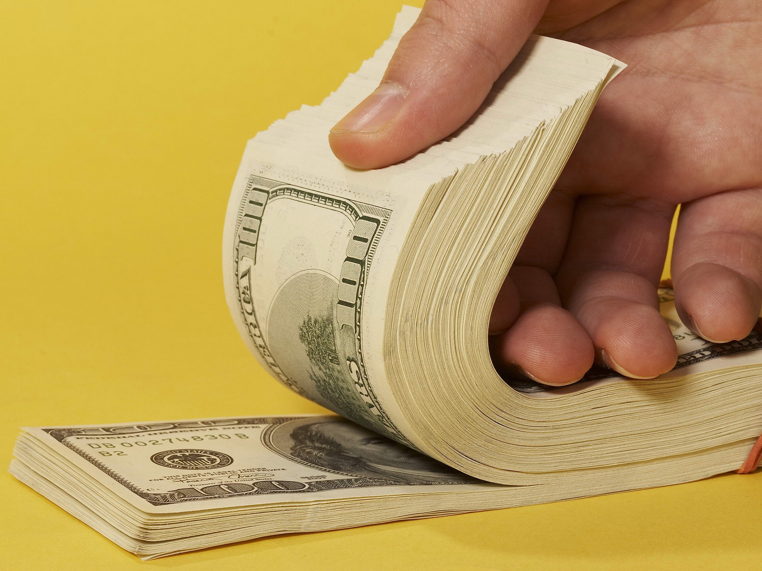 Hand holding a stack of US dollar bills HD Wallpaper