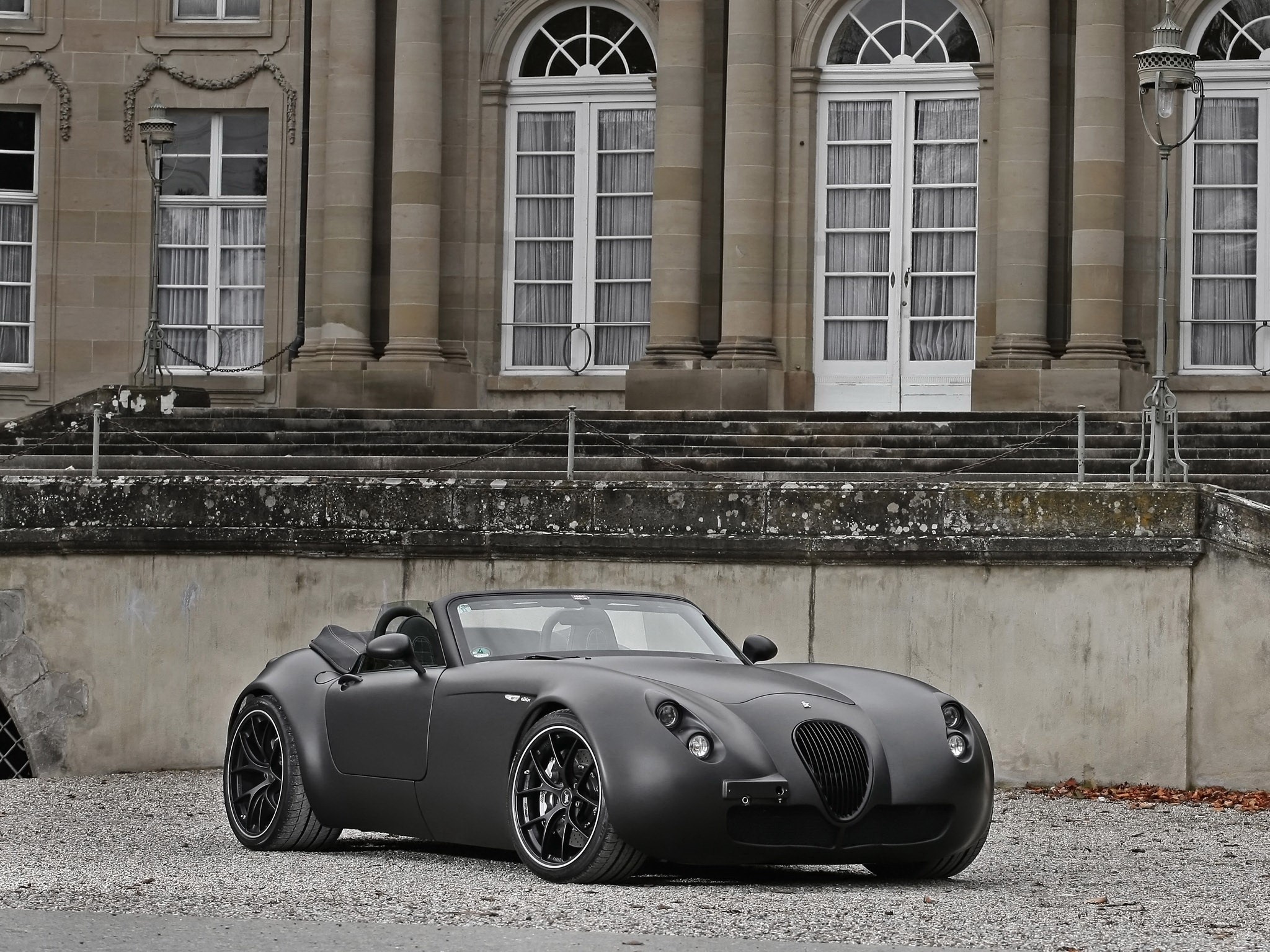 Matte black Wiesmann convertible sports car in front of a mansion HD Wallpaper