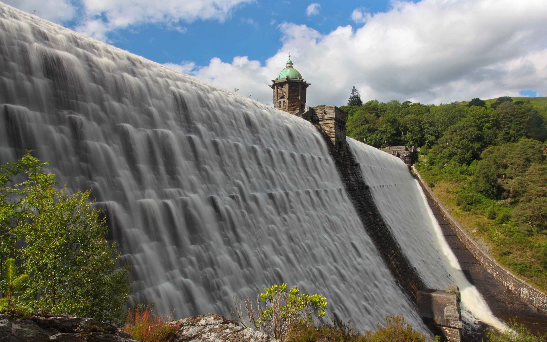 Water cascading over a large dam with a tower HD Wallpaper
