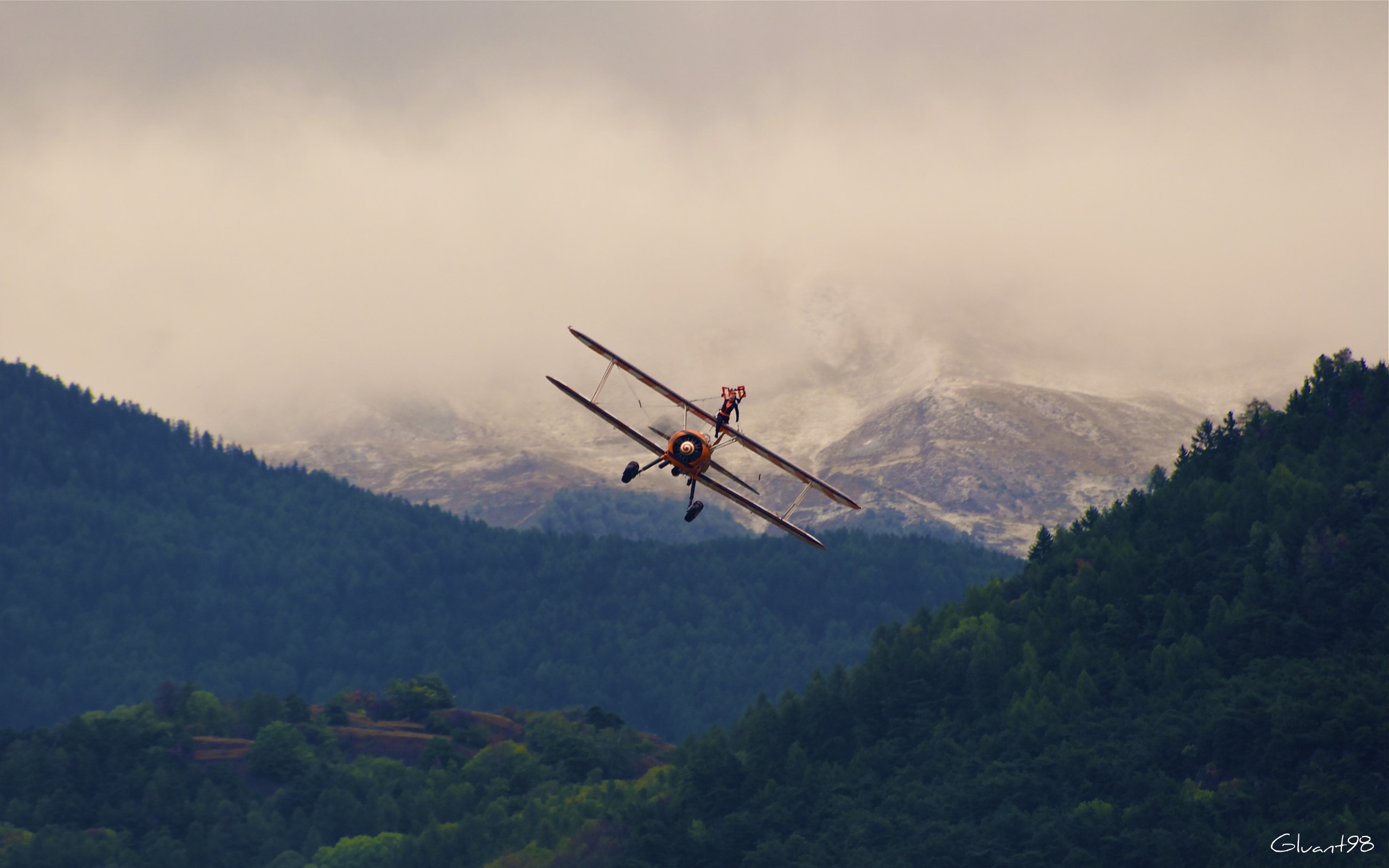 Biplane with wing walker over mountains HD Wallpaper