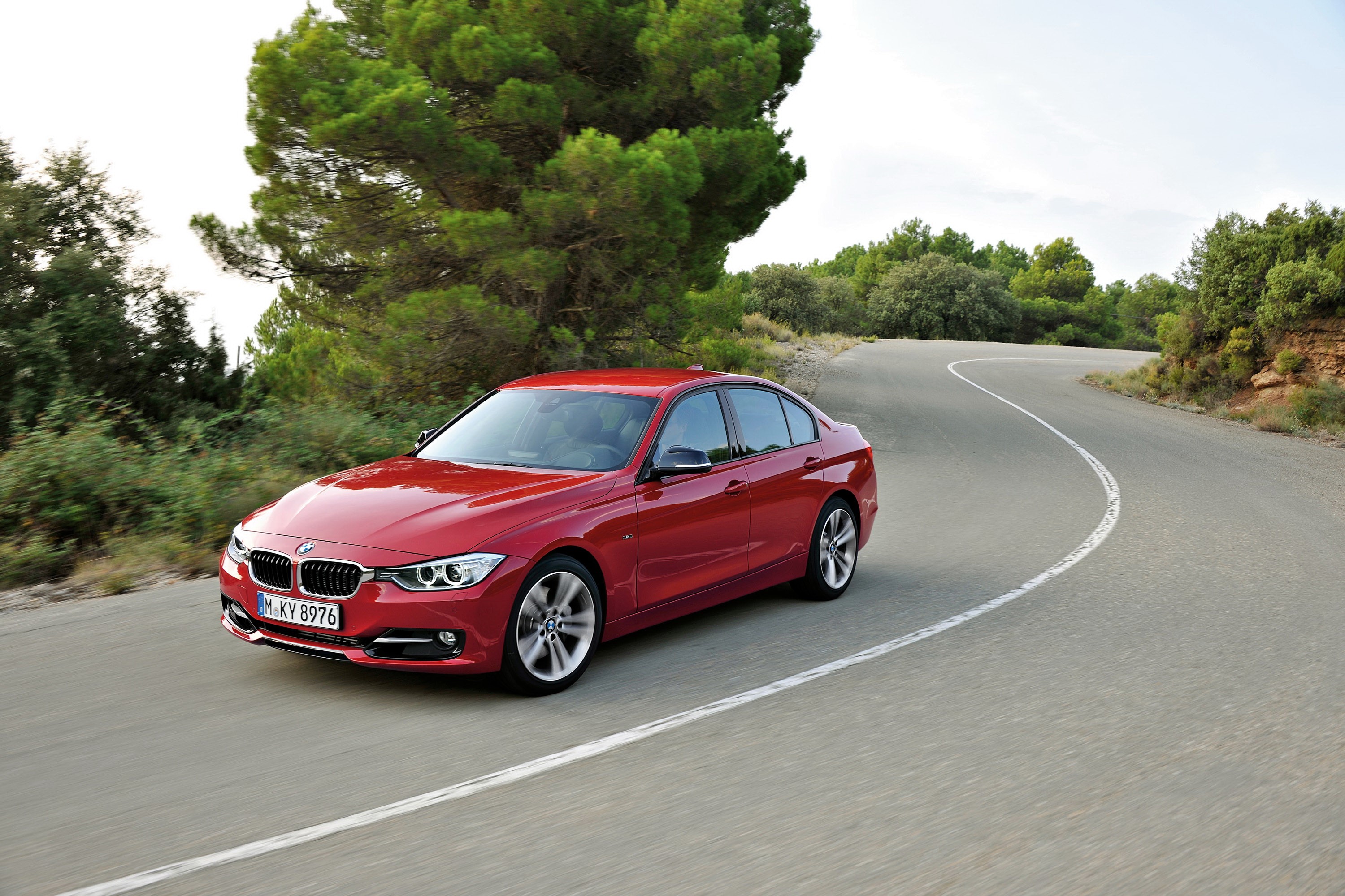 Red BMW sedan driving on a winding road HD Wallpaper