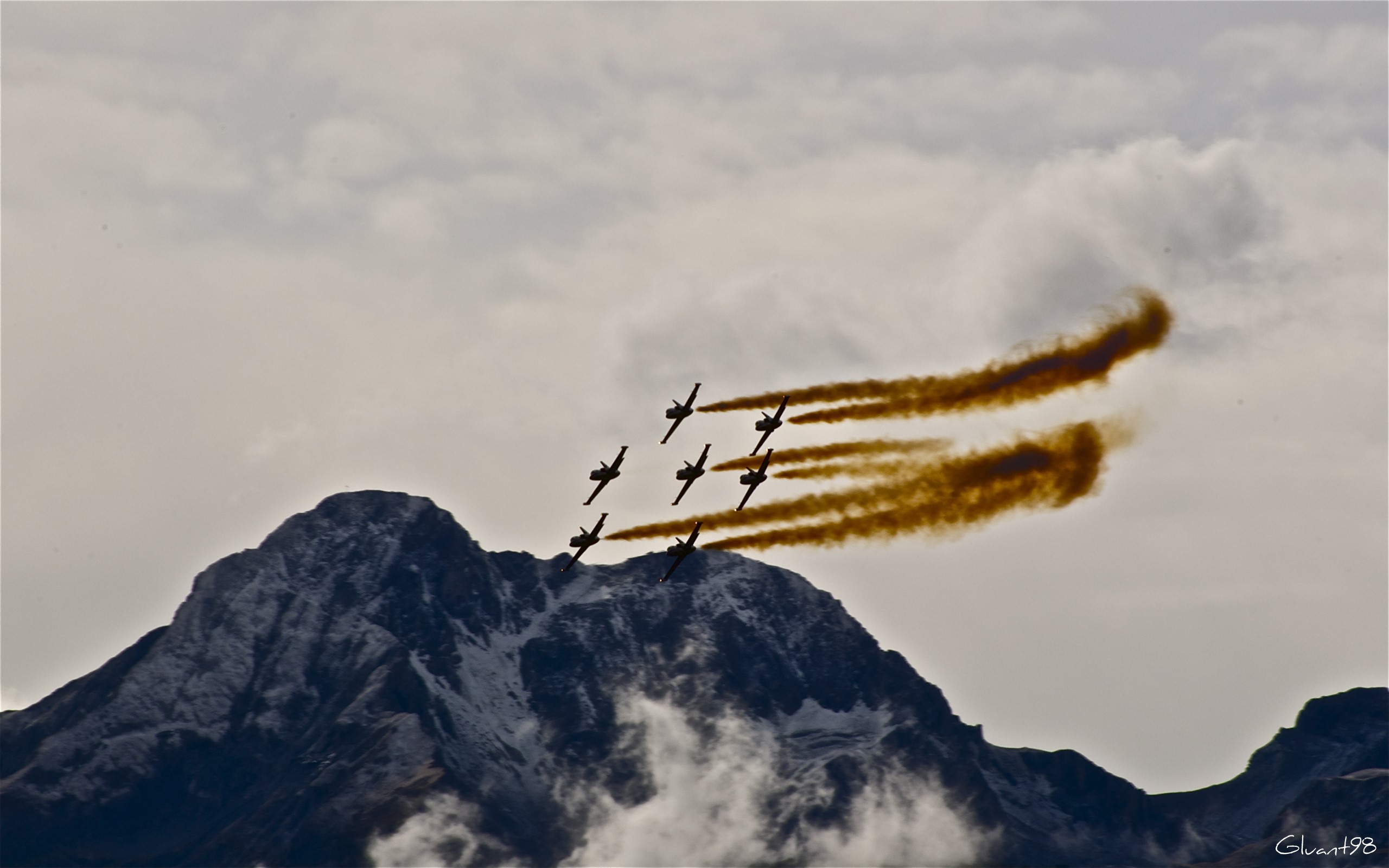 Airplanes performing aerobatics over a snowy mountain HD Wallpaper