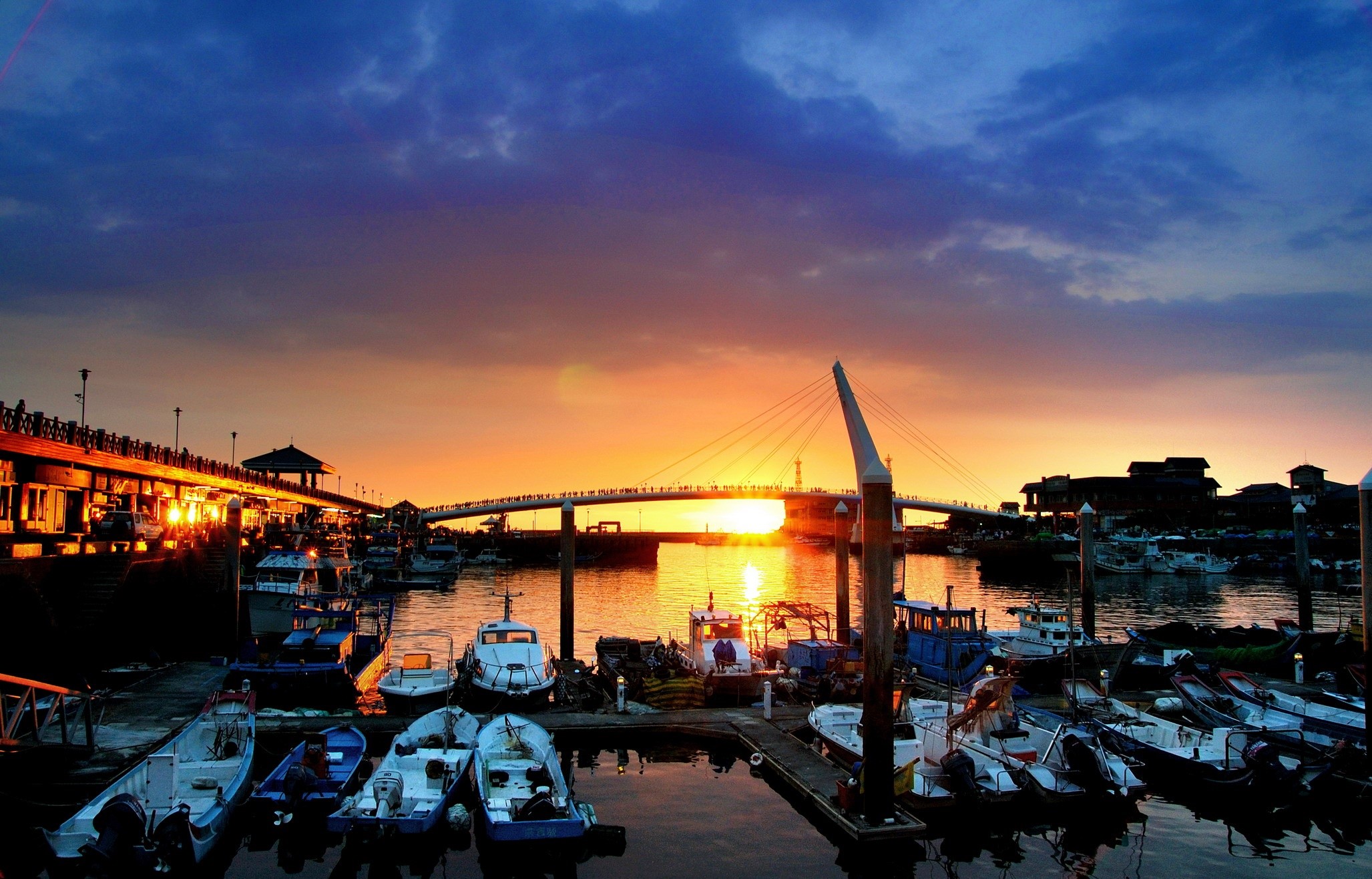 Boats docked at a harbor during sunset with a bridge HD Wallpaper